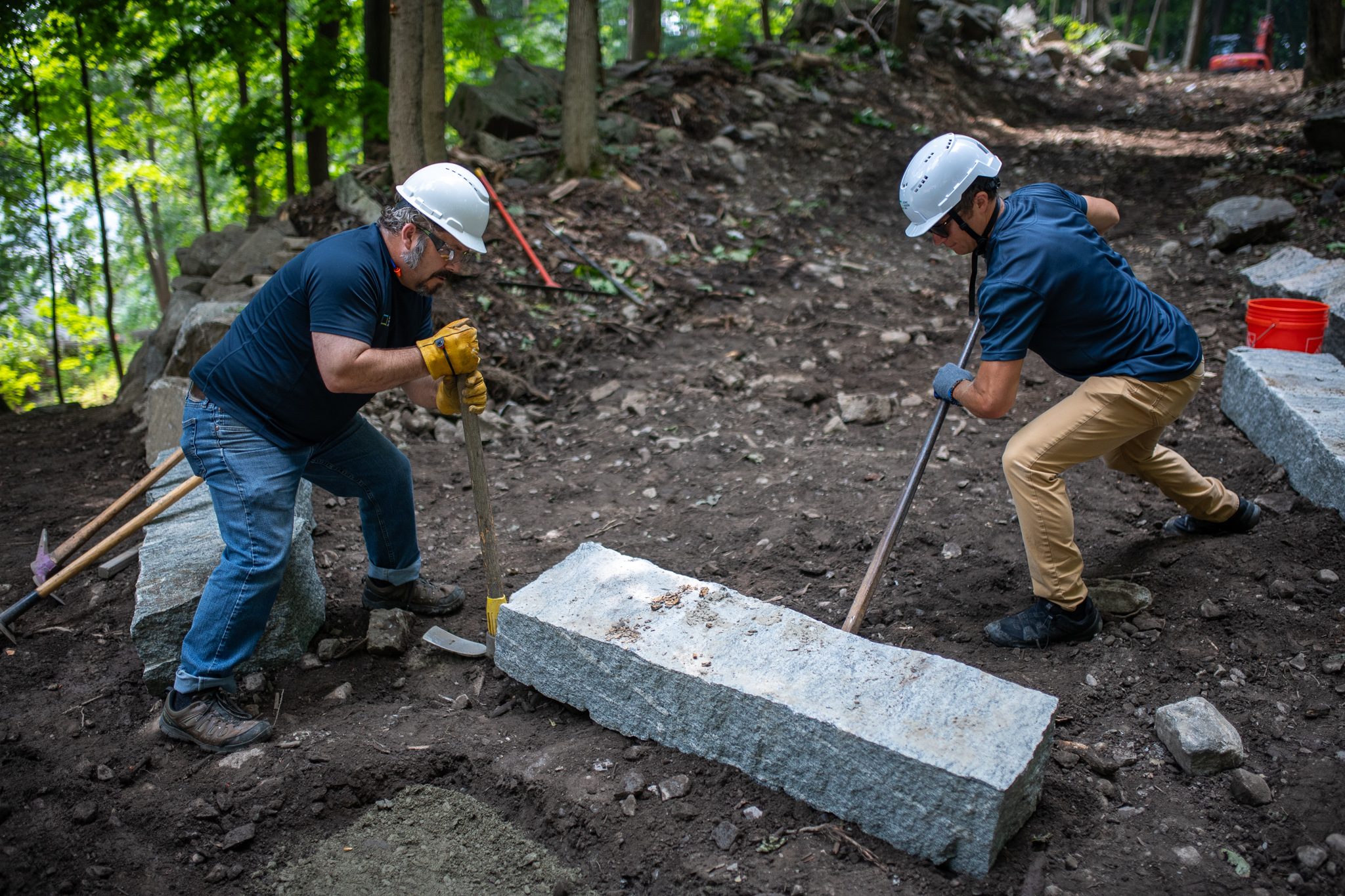Two men set their bars on either side of a granite step.