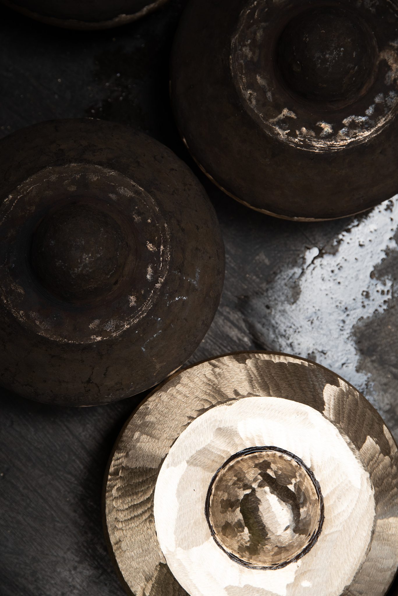Unpolished gongs crowd around one freshly finished, its face bright as a coin.