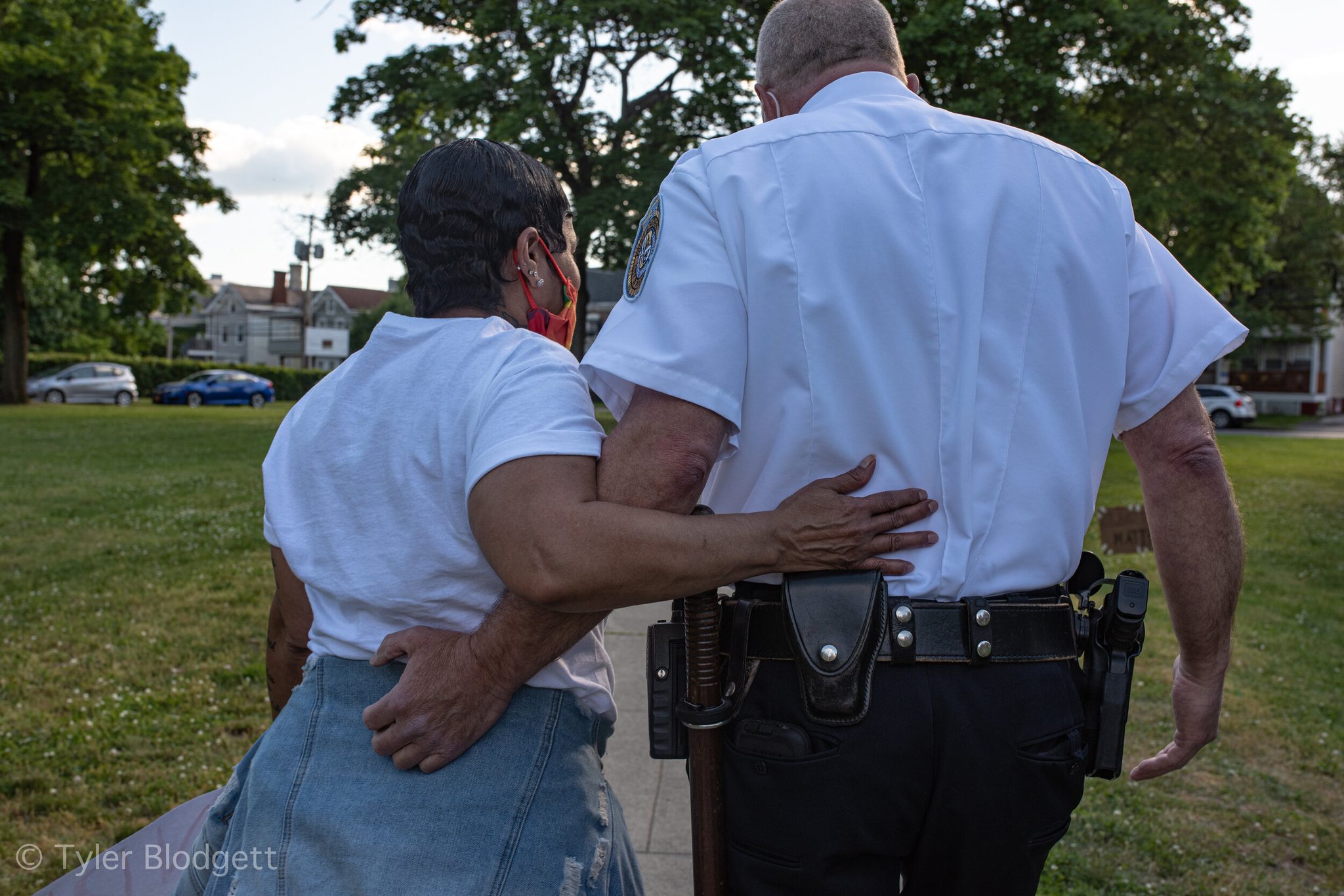 A woman and an officer walk arm in arm across the green.