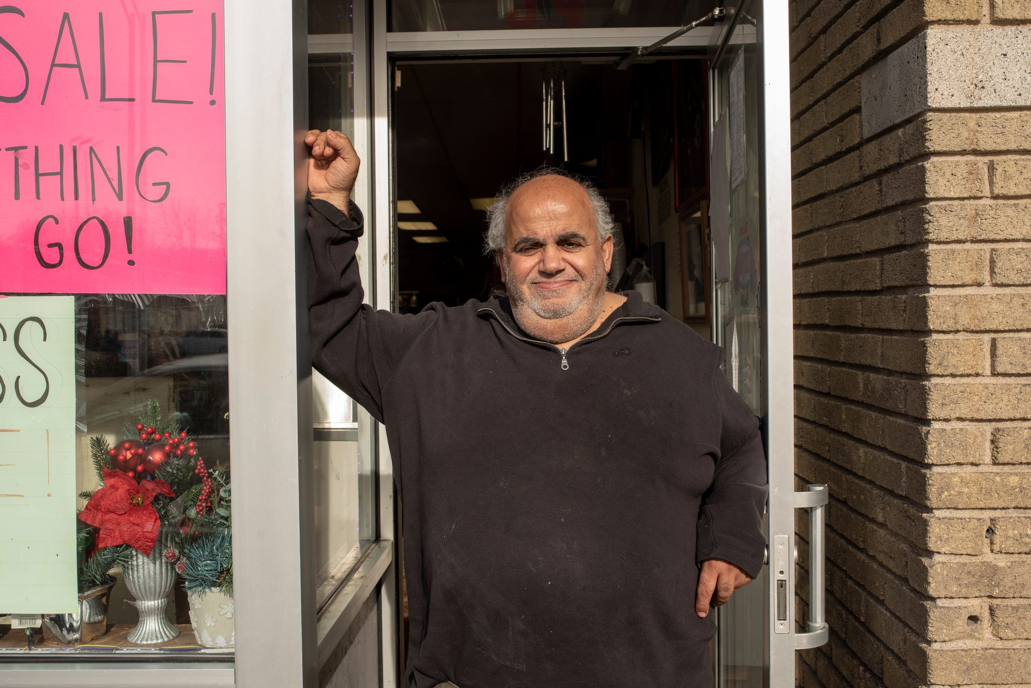 A shopkeeper raises a fist from his doorway as the cleanup passes.