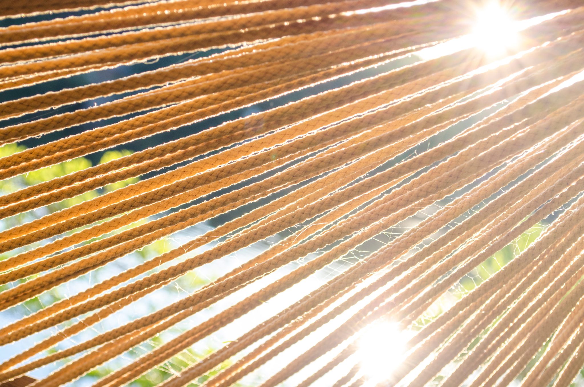 Sunlight flares through strands of woven rope.