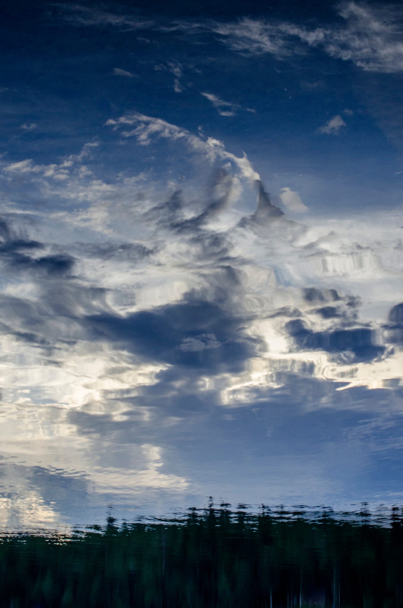 Clouds billow across the sky and down into the still lake.