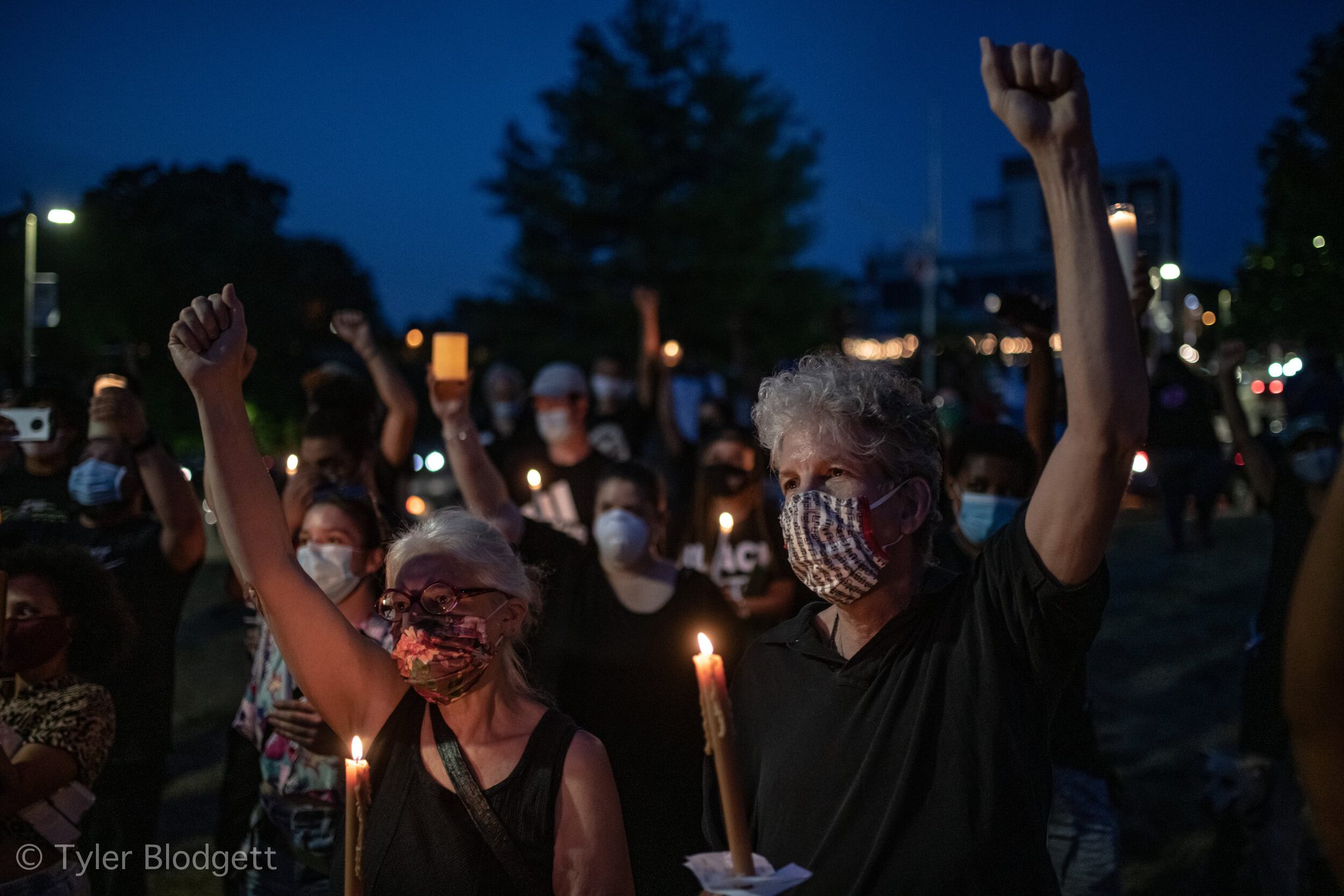 Fists rise over the candles as the vigil fills the dark.