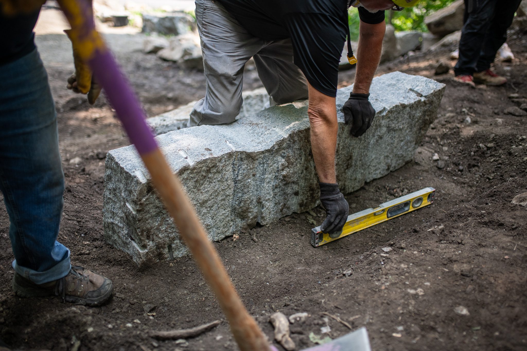 A level checks the face of a granite step.