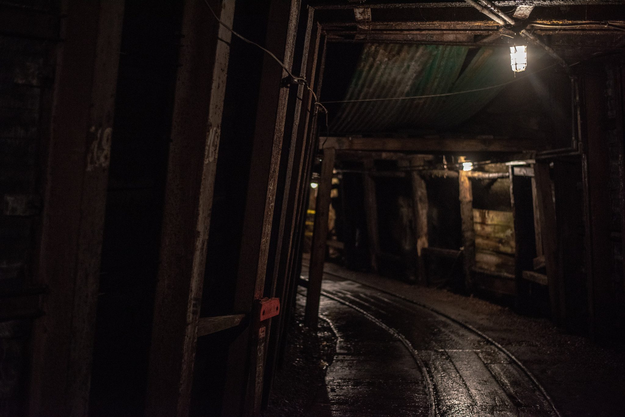 Timbered tunnels and narrow rails run off into the dark of an old coal mine.