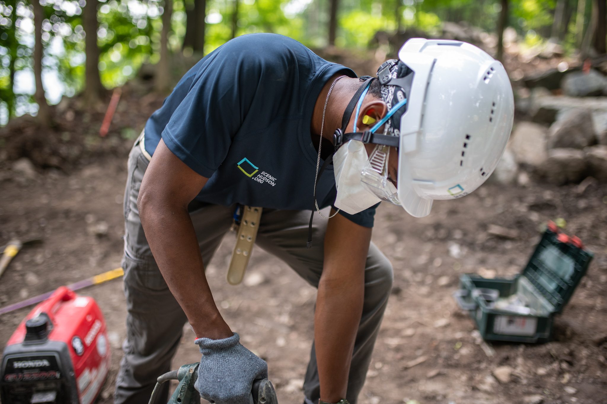 He bends close over the drill, a generator humming beside him.