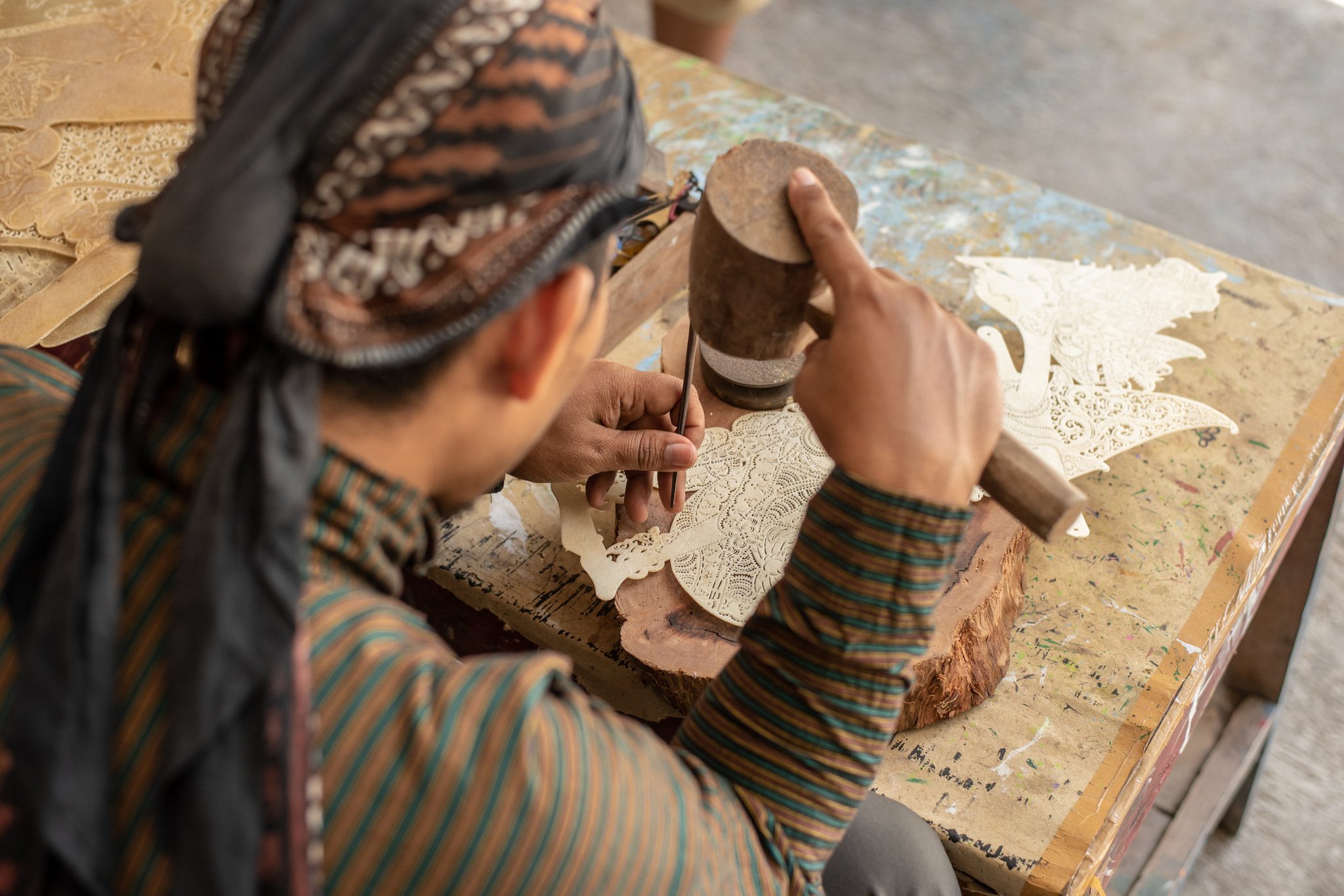 Tap by tap, the mallet drives the chisel through the leather.