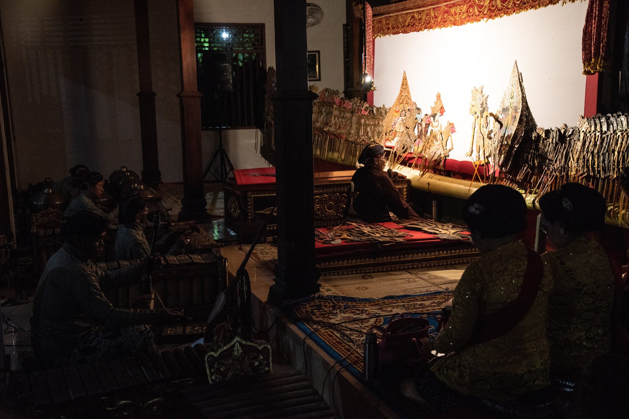 In the dark of the pavilion, the gamelan players follow the dalang's lead.