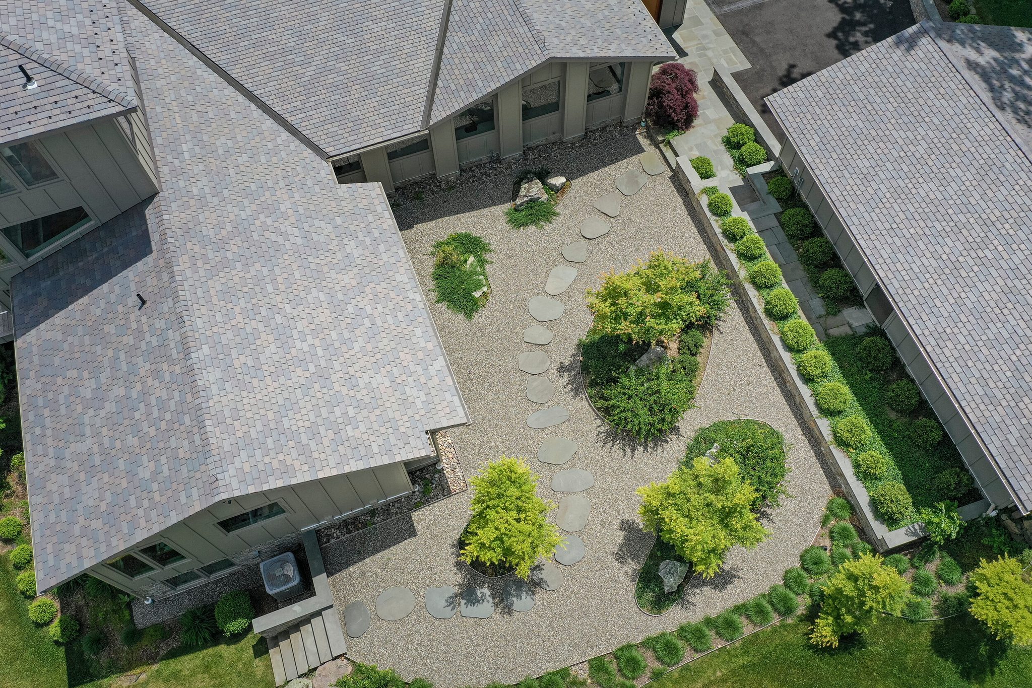 From above, a stepping-stone path winds through the gravel courtyard between the wings.