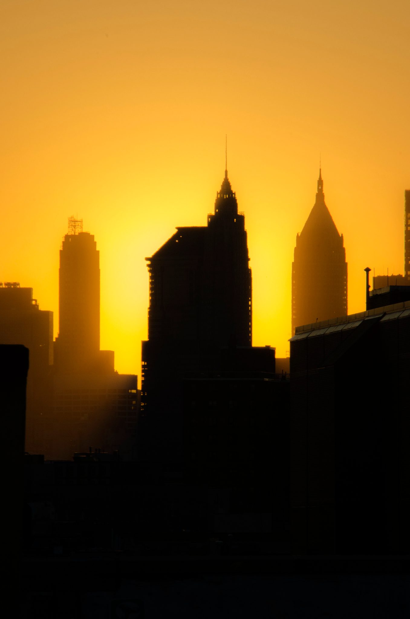 From Brooklyn, the Manhattan skyline burns down to silhouette at sunset.