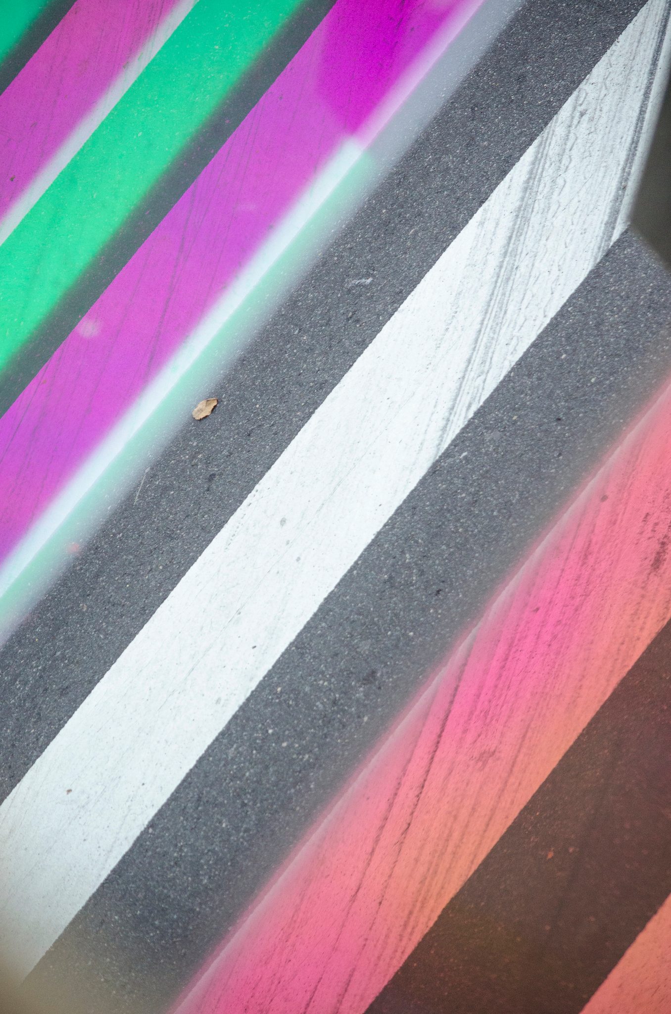 Stripes of pink and green light slant across a concrete wall.