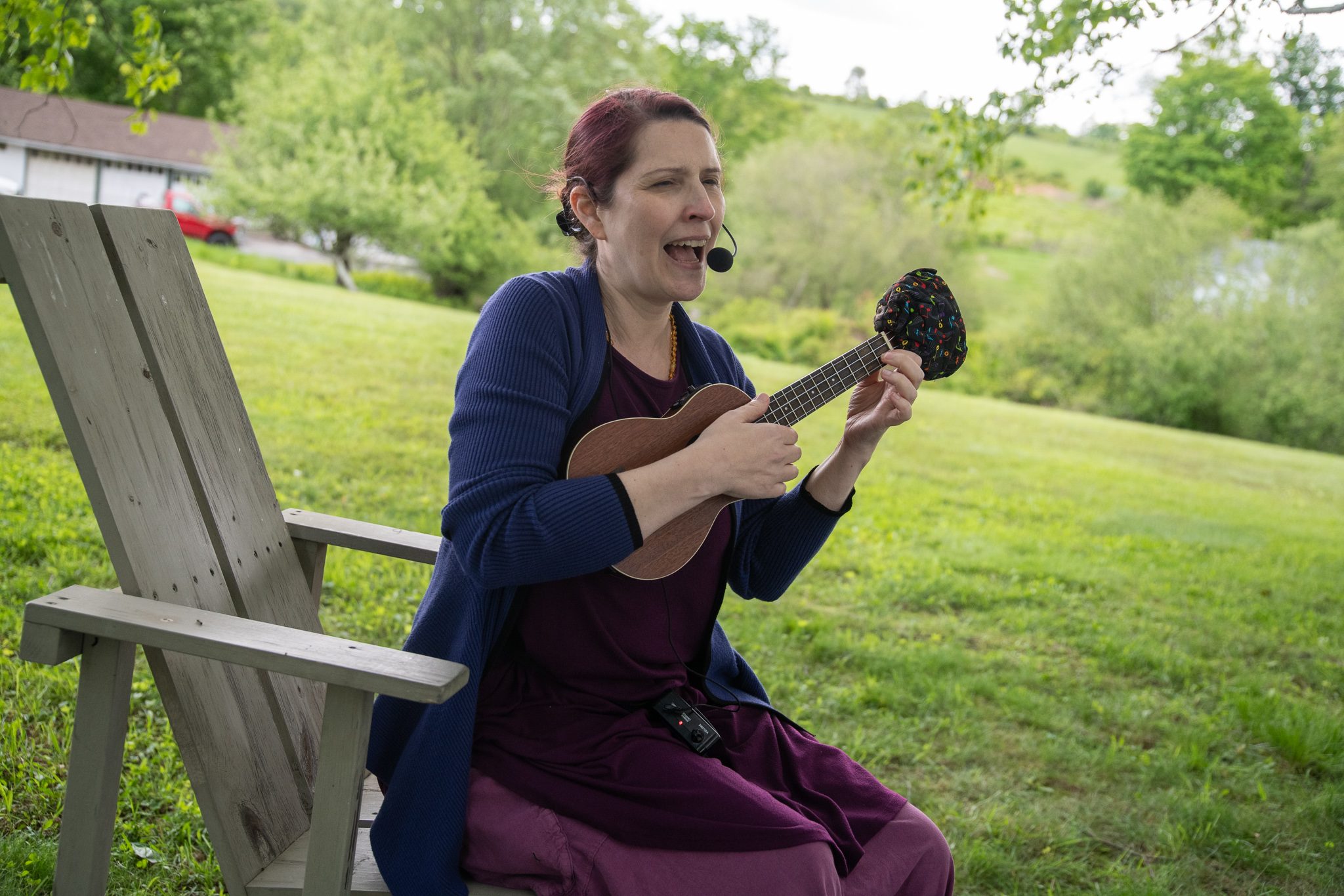 A singer strums her ukulele from an Adirondack chair on the lawn.