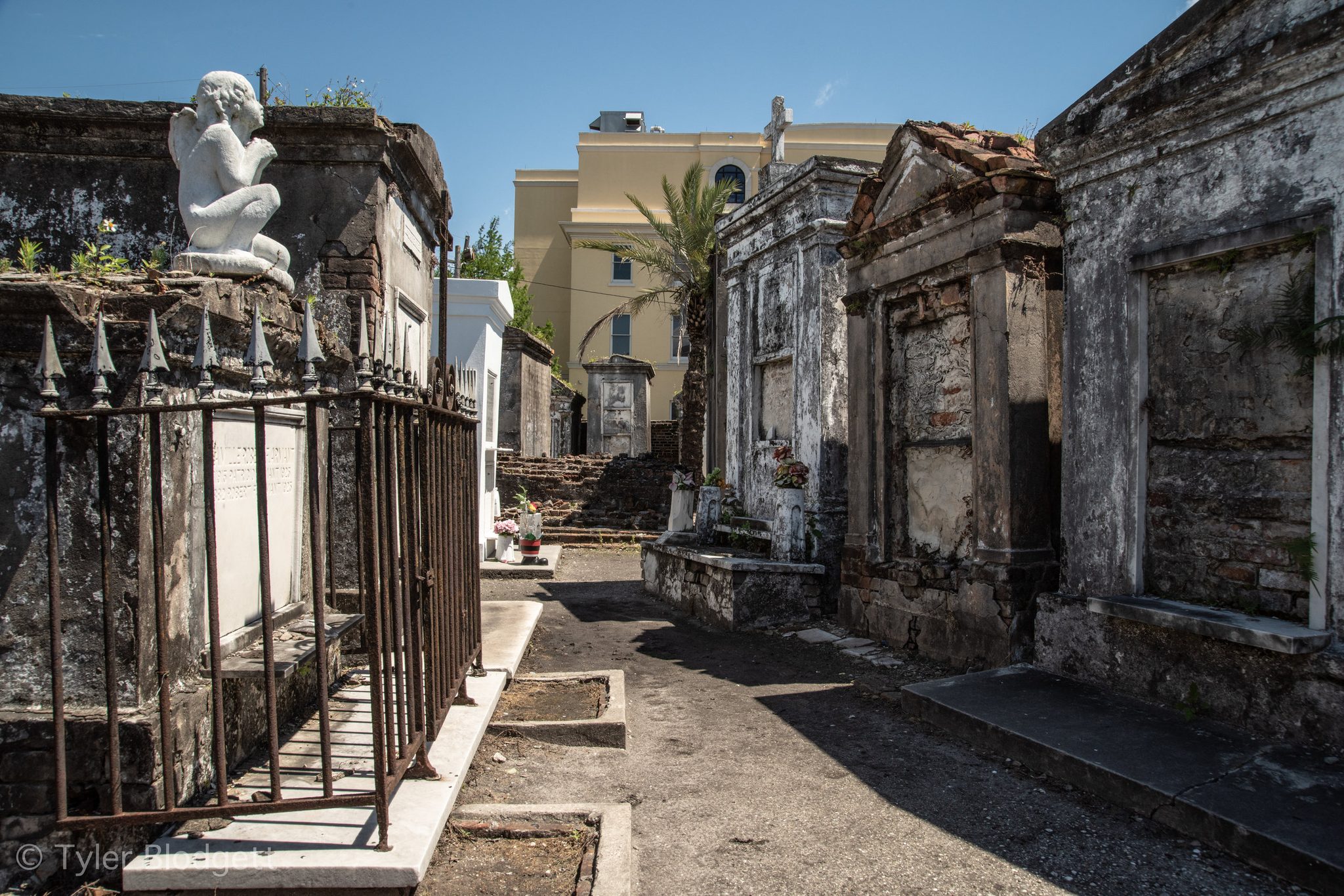 An angel keeps watch over the tombs in a cemetery of whitewashed stone.