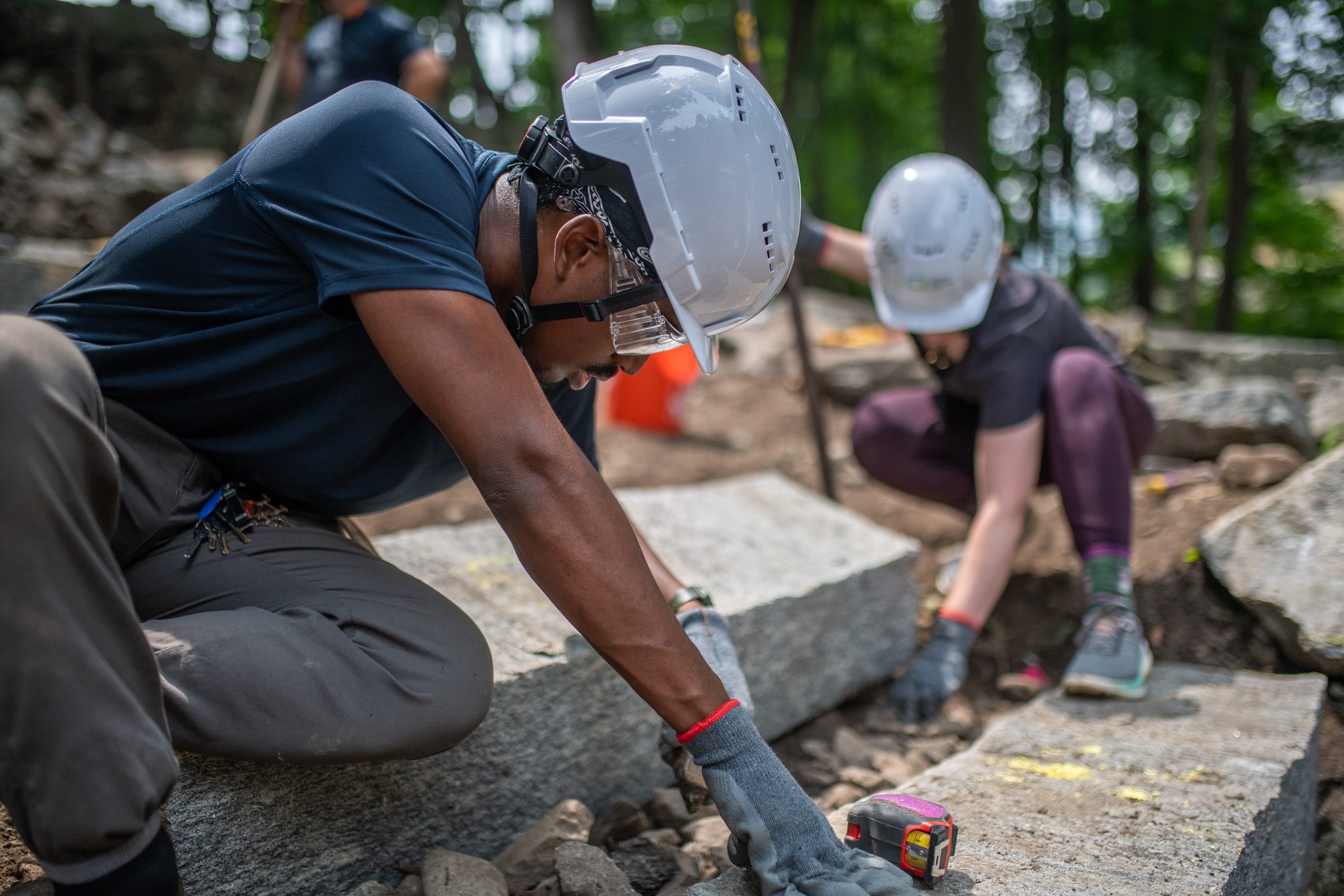 Two crew members fit the stones together, one kneeling on each side.
