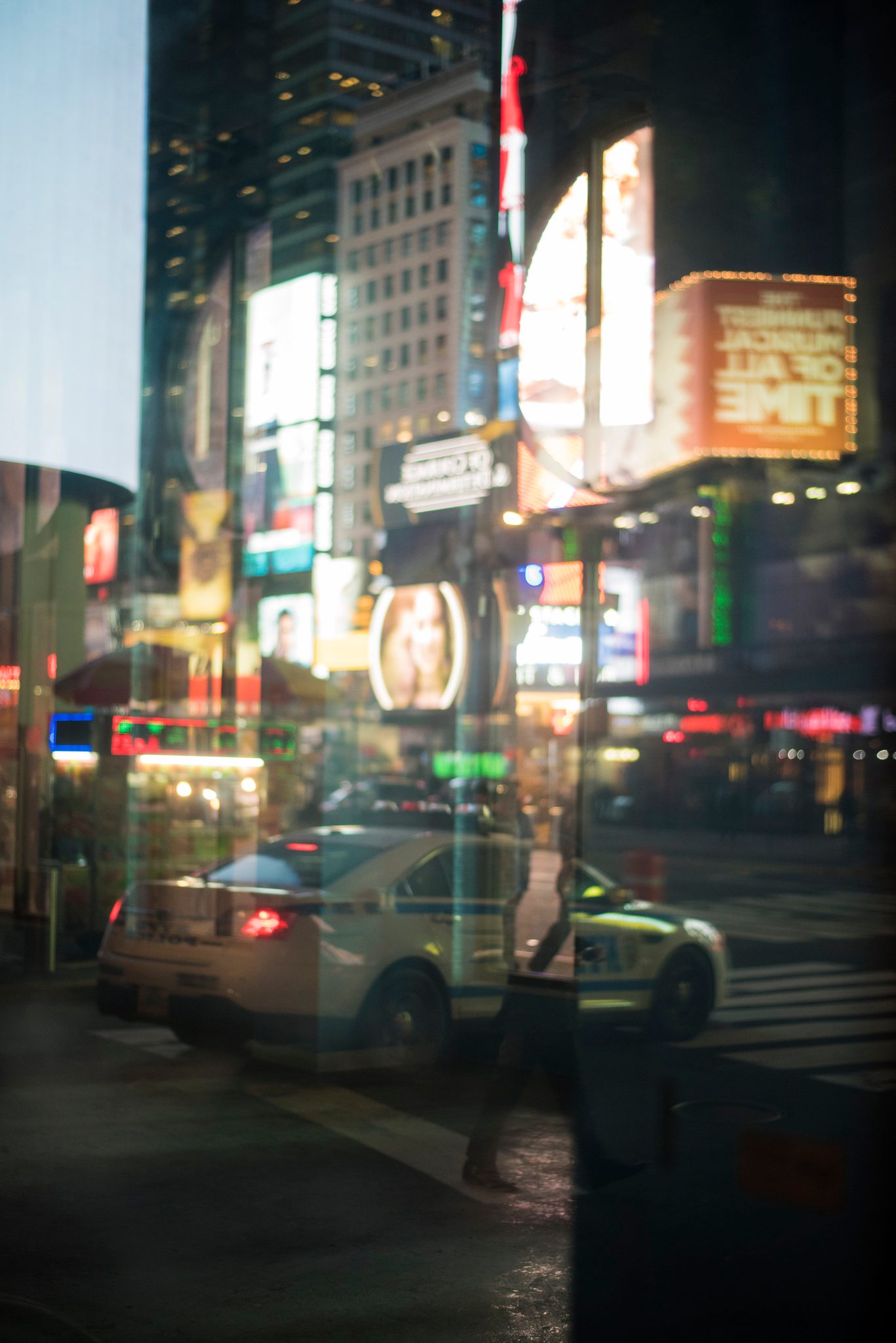 Billboards, taxis and passersby dissolve into one another in a Manhattan window.