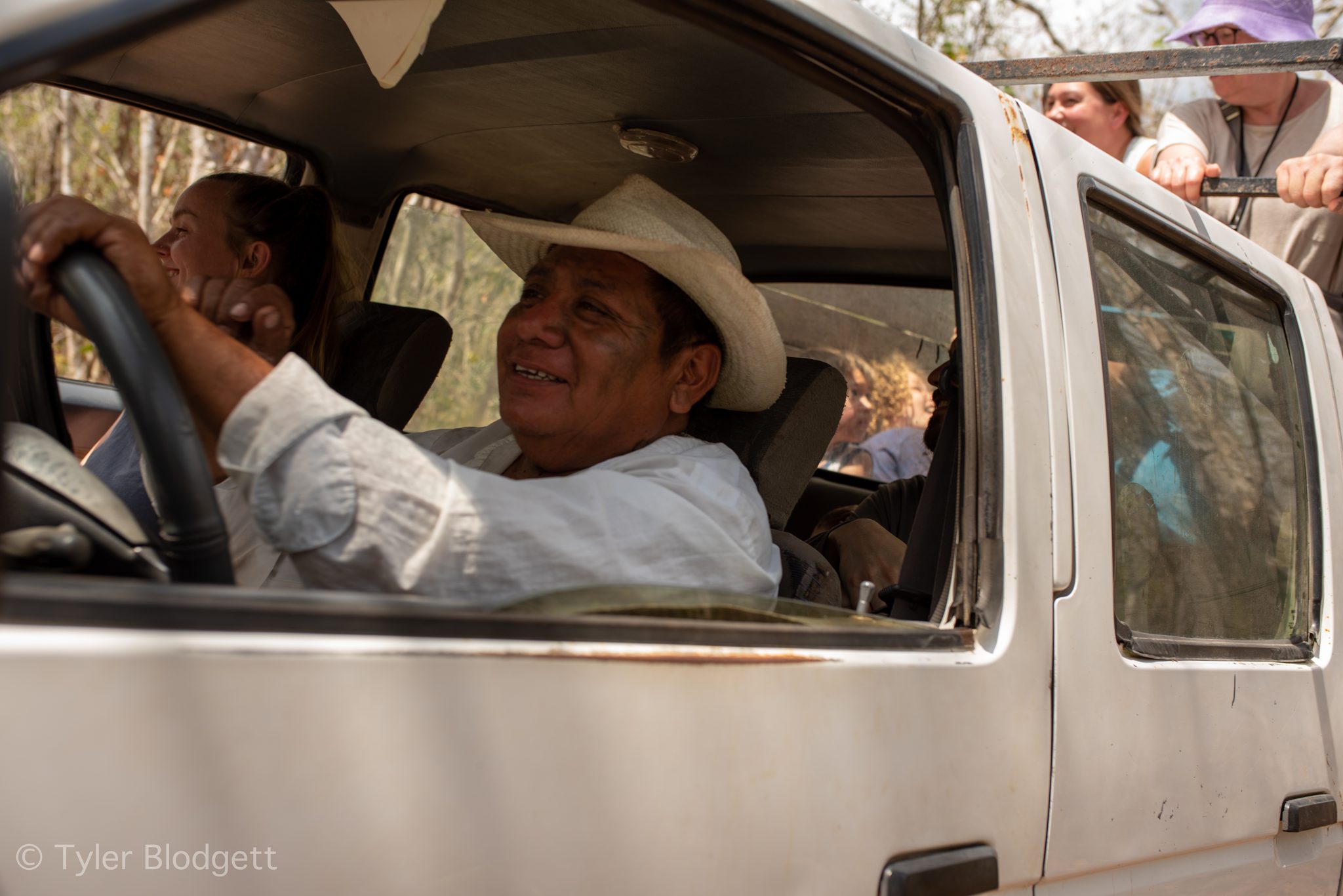 The elder grins from behind the wheel of a white pickup.