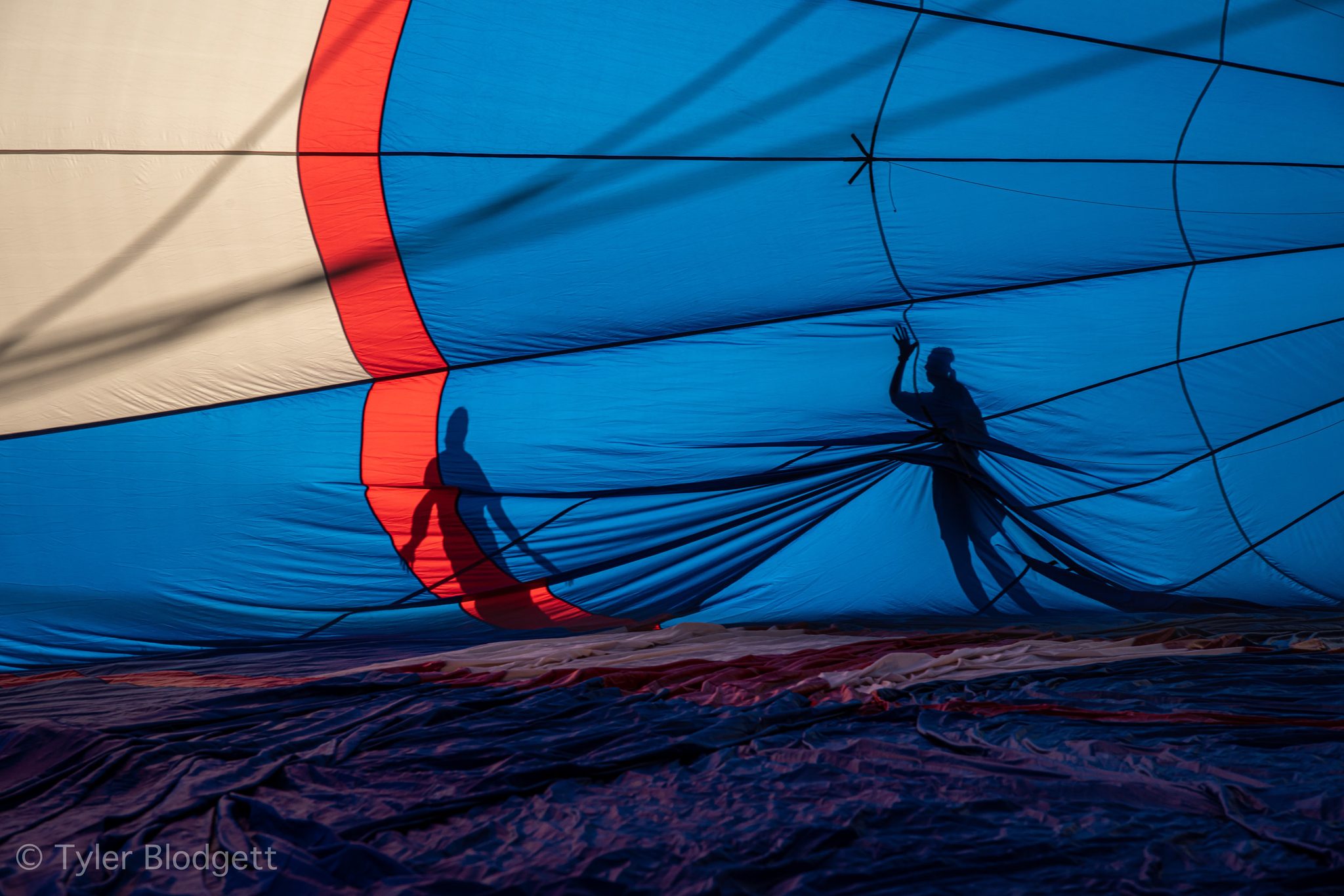 Shadows of the crew stretch across the fabric as the balloon takes its first breath.