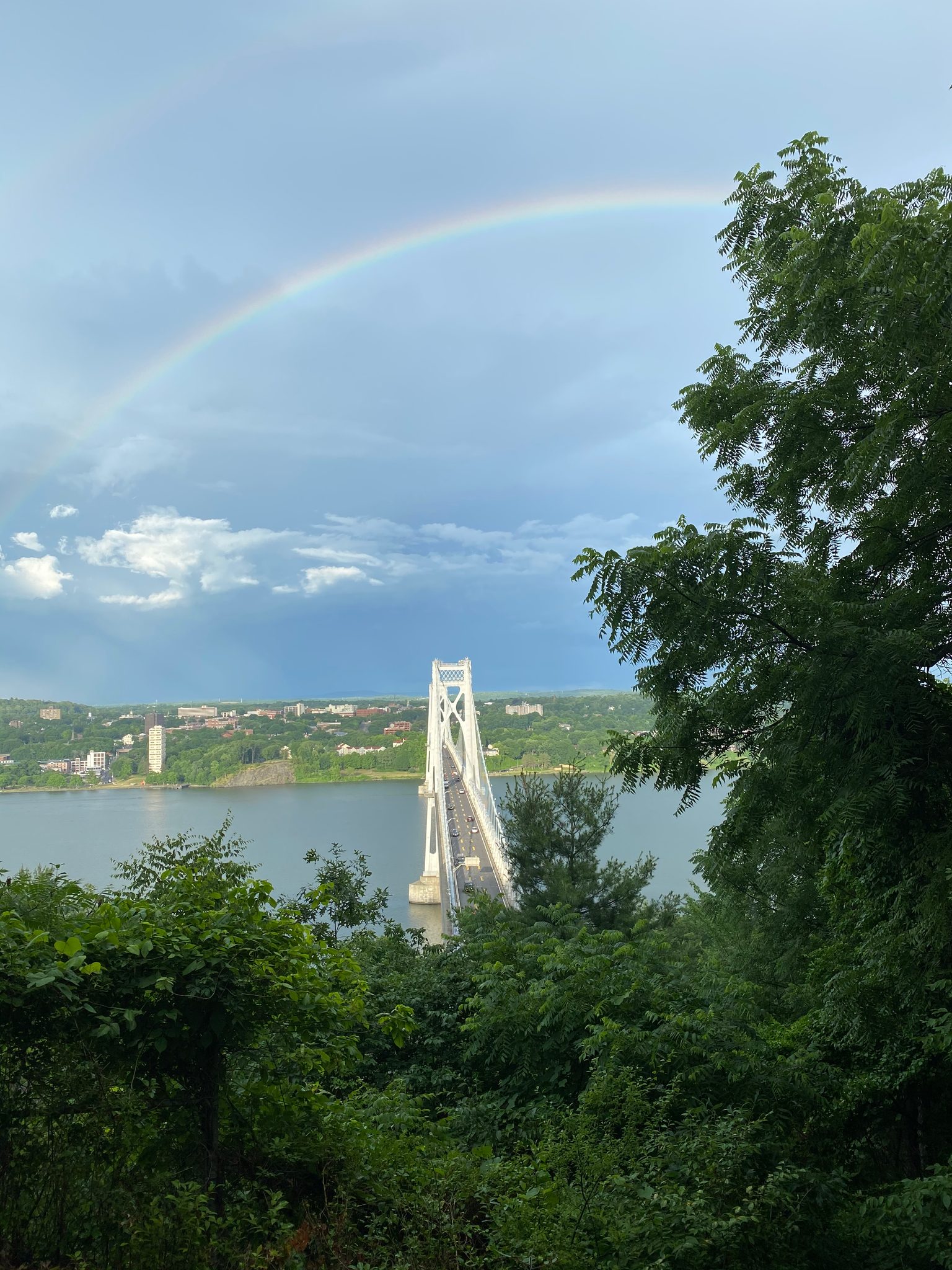 A double rainbow arcs over the bridge and the far shore.