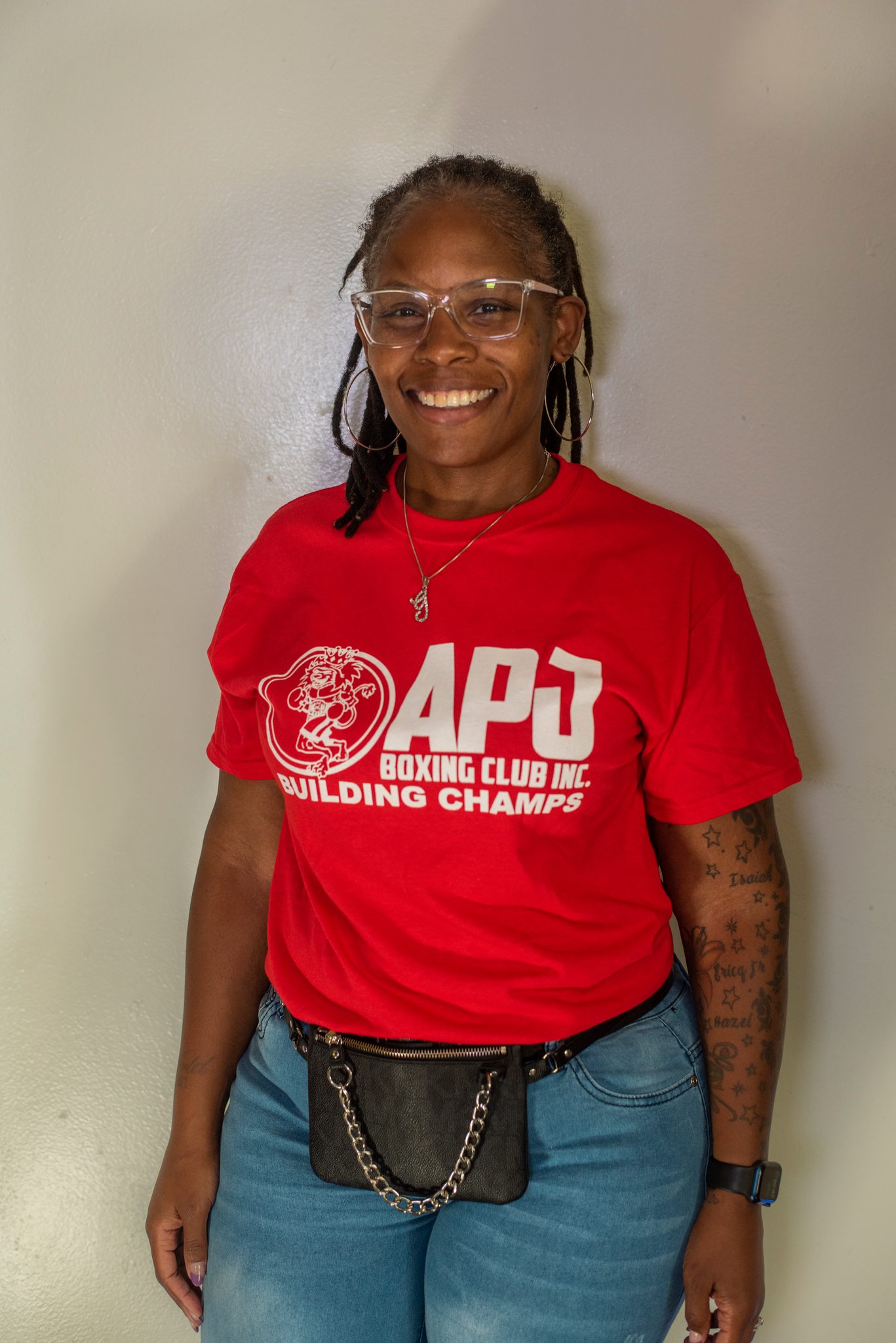 A club member smiles in the red shirt, glasses and braids.