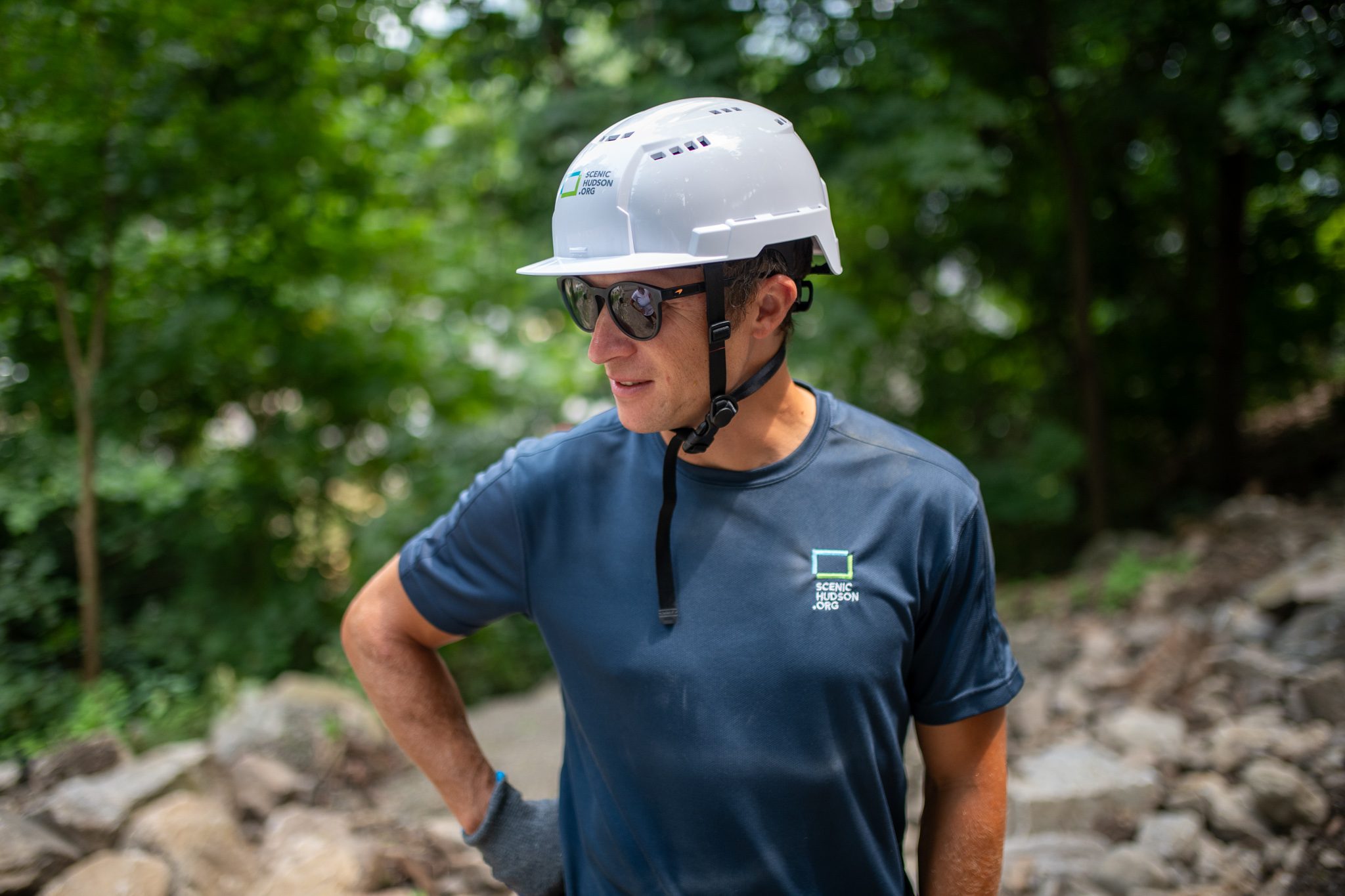 A crew member glances off down the trail, hand on his hip.