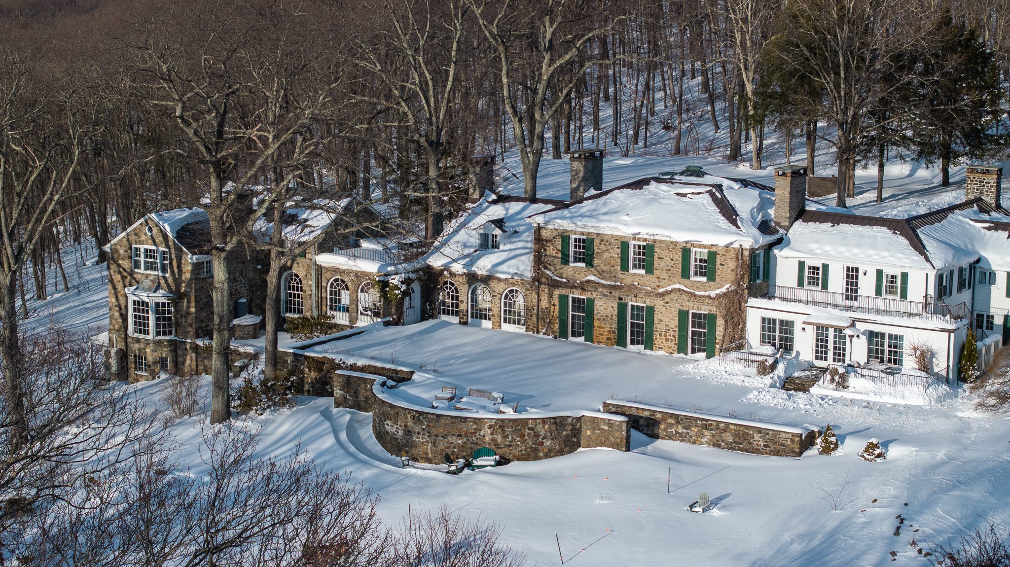 The stone manor from above, its terraces and rooftops deep in snow.