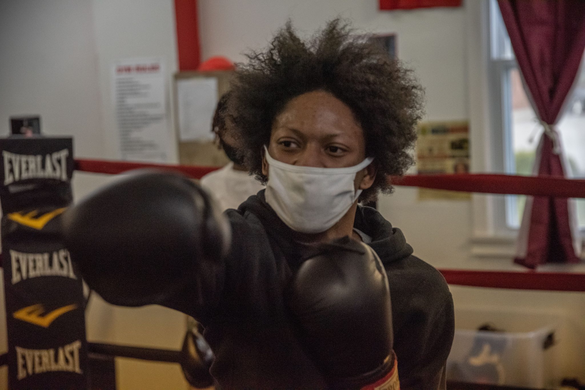 A masked boxer throws a jab across the ring.