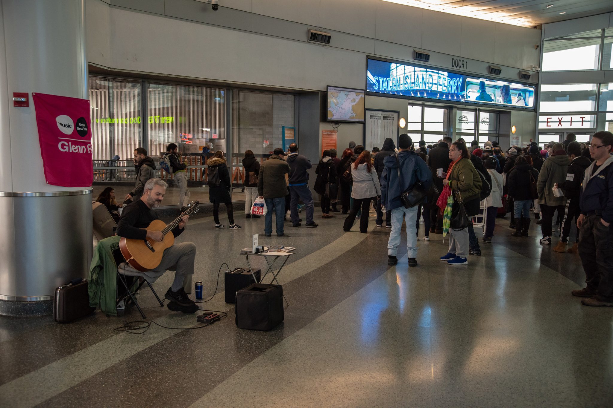 Glenn plays under his banner at the ferry terminal as the crowd waits to board.