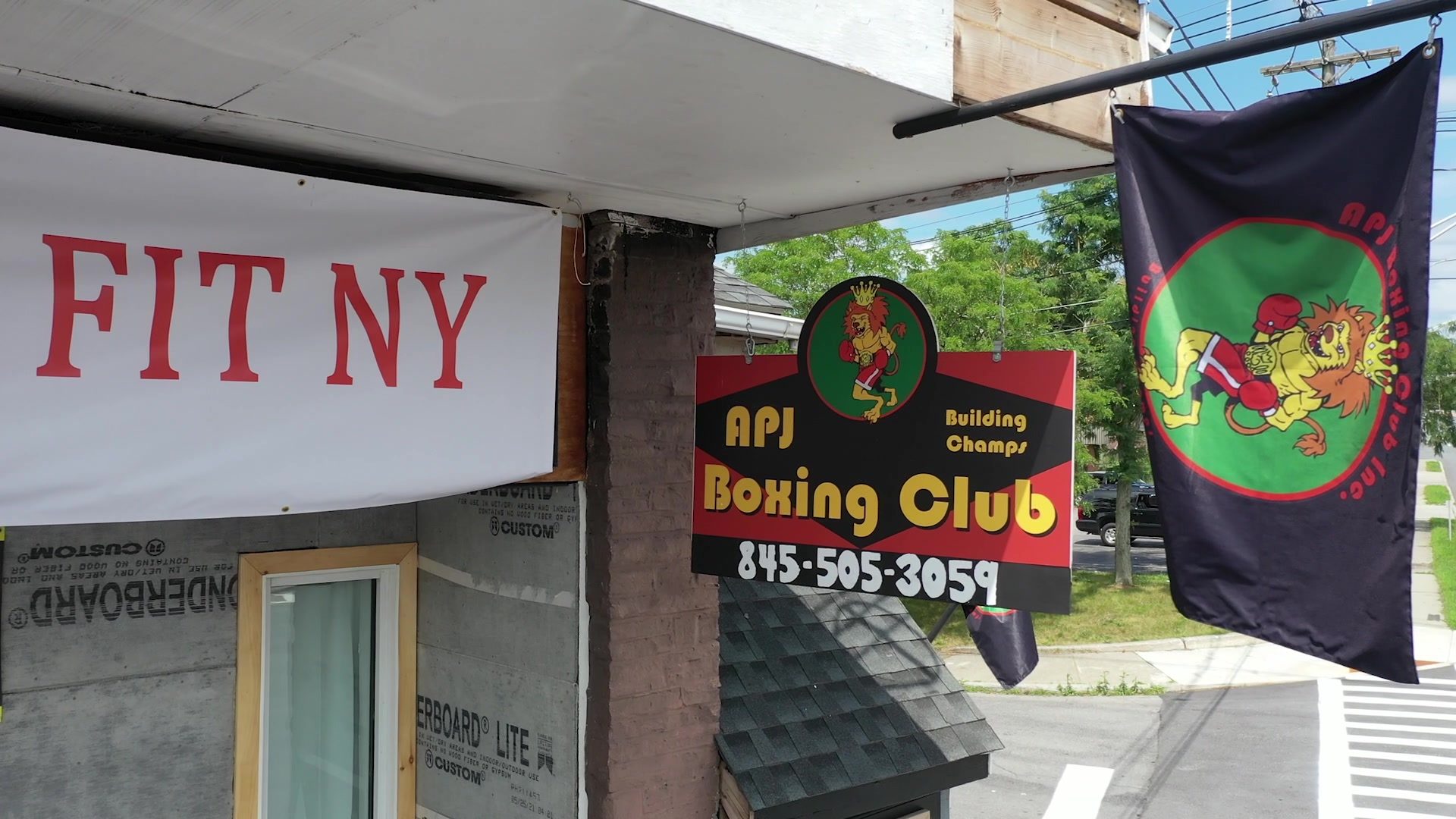 The lion flag and the hanging club sign turn in the breeze at the corner, with the crosswalk just beyond.
