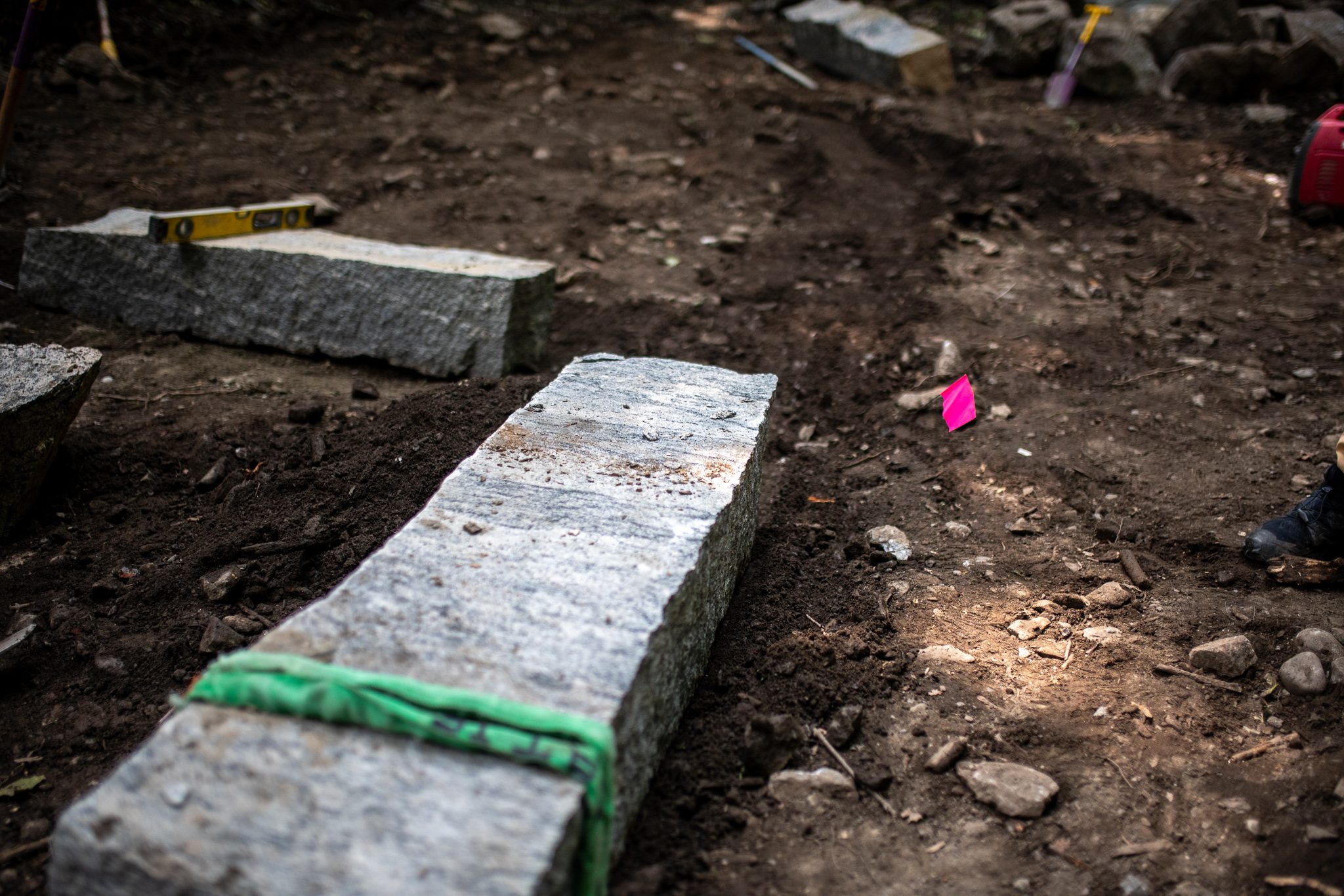 A green strap wraps a granite step ready to be hauled.