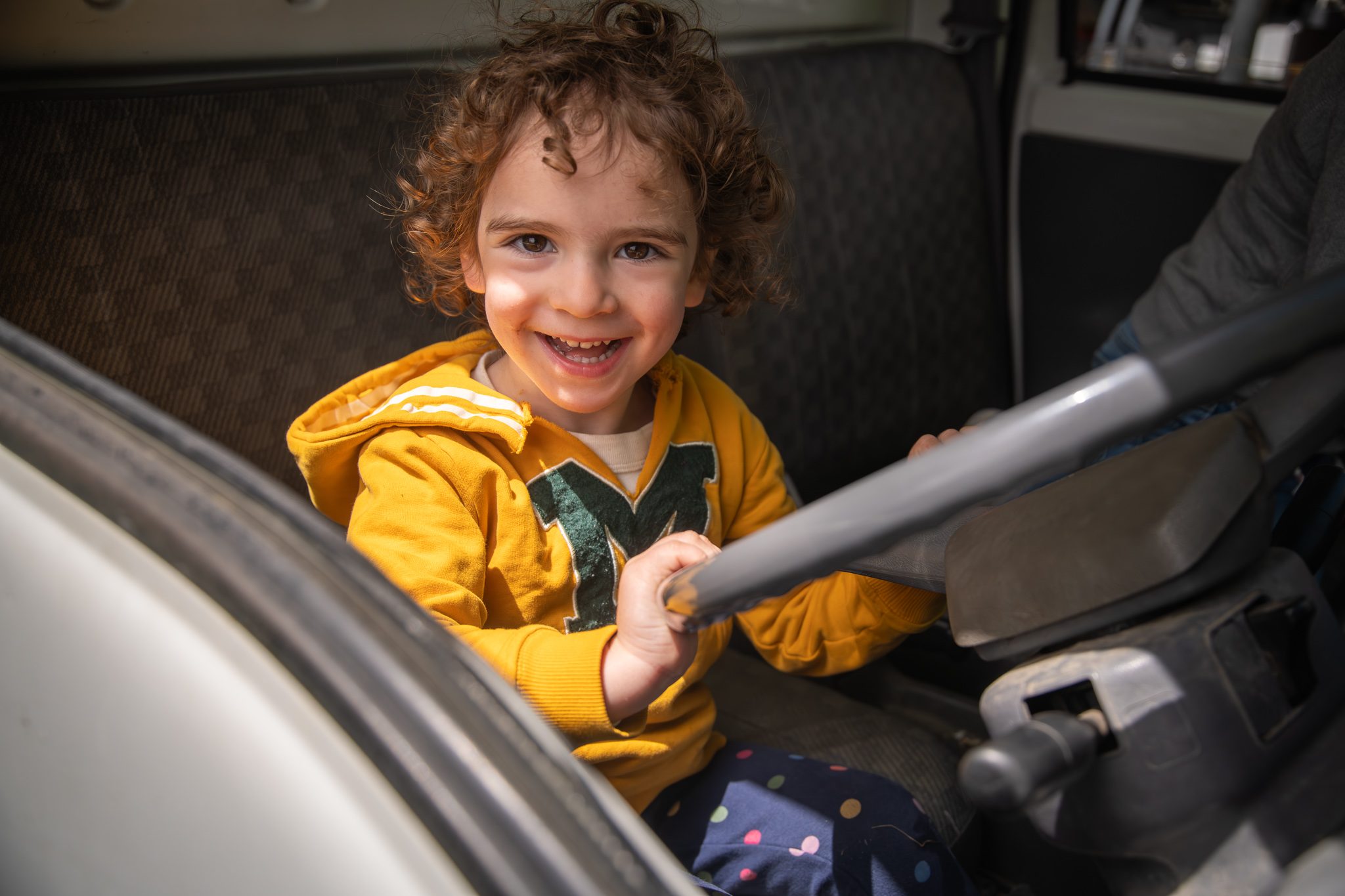 A boy takes the wheel of the truck and can't stop grinning.