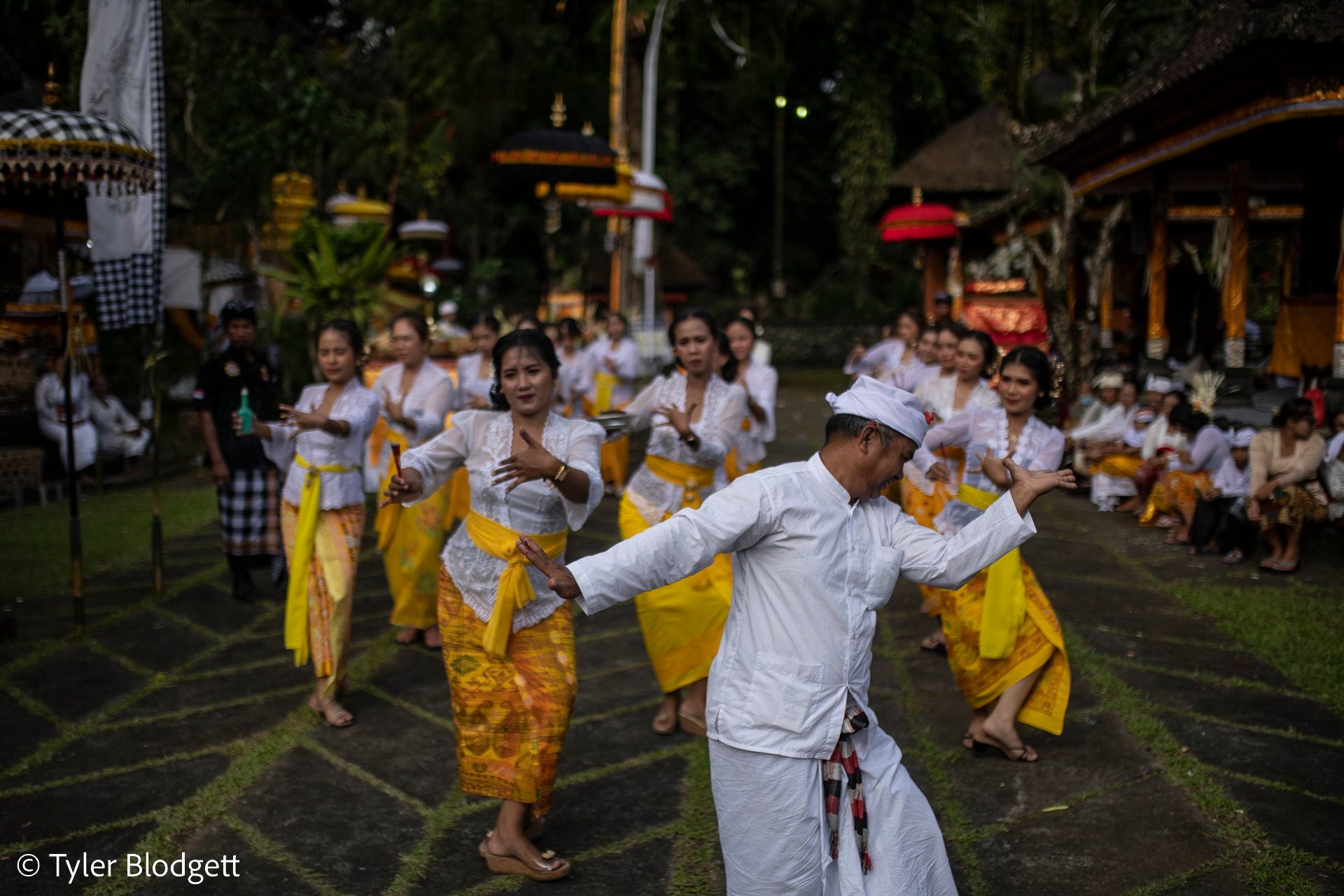 A man in white joins the dancing women, arms out, finding the same slow rhythm.