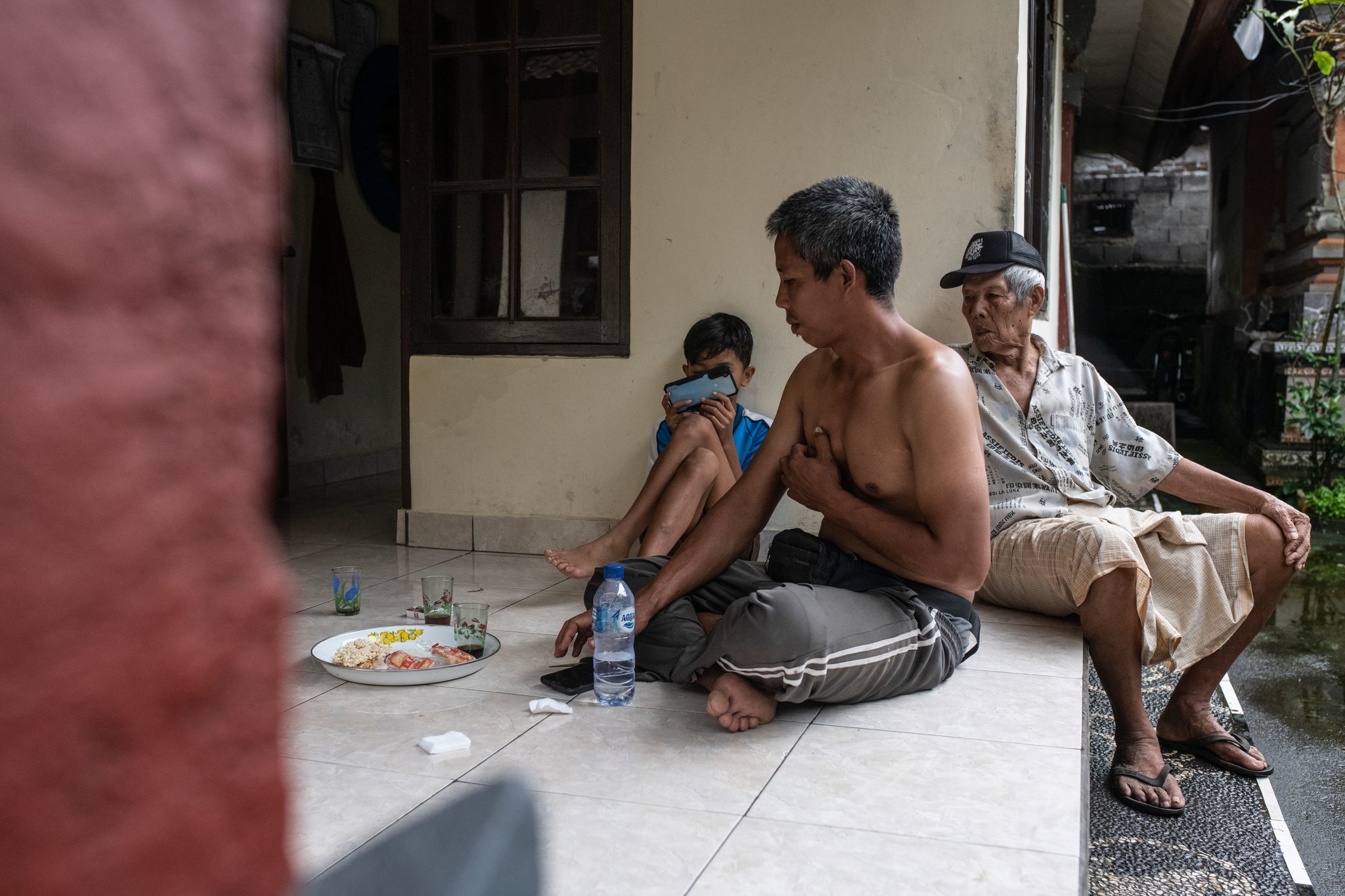 Three generations share a meal on the tiled porch.