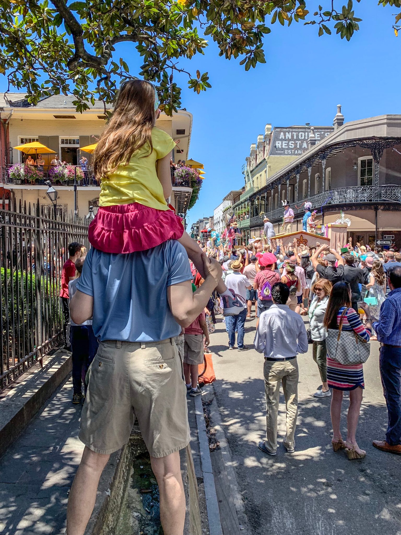 A girl rides her father's shoulders above the crowd.