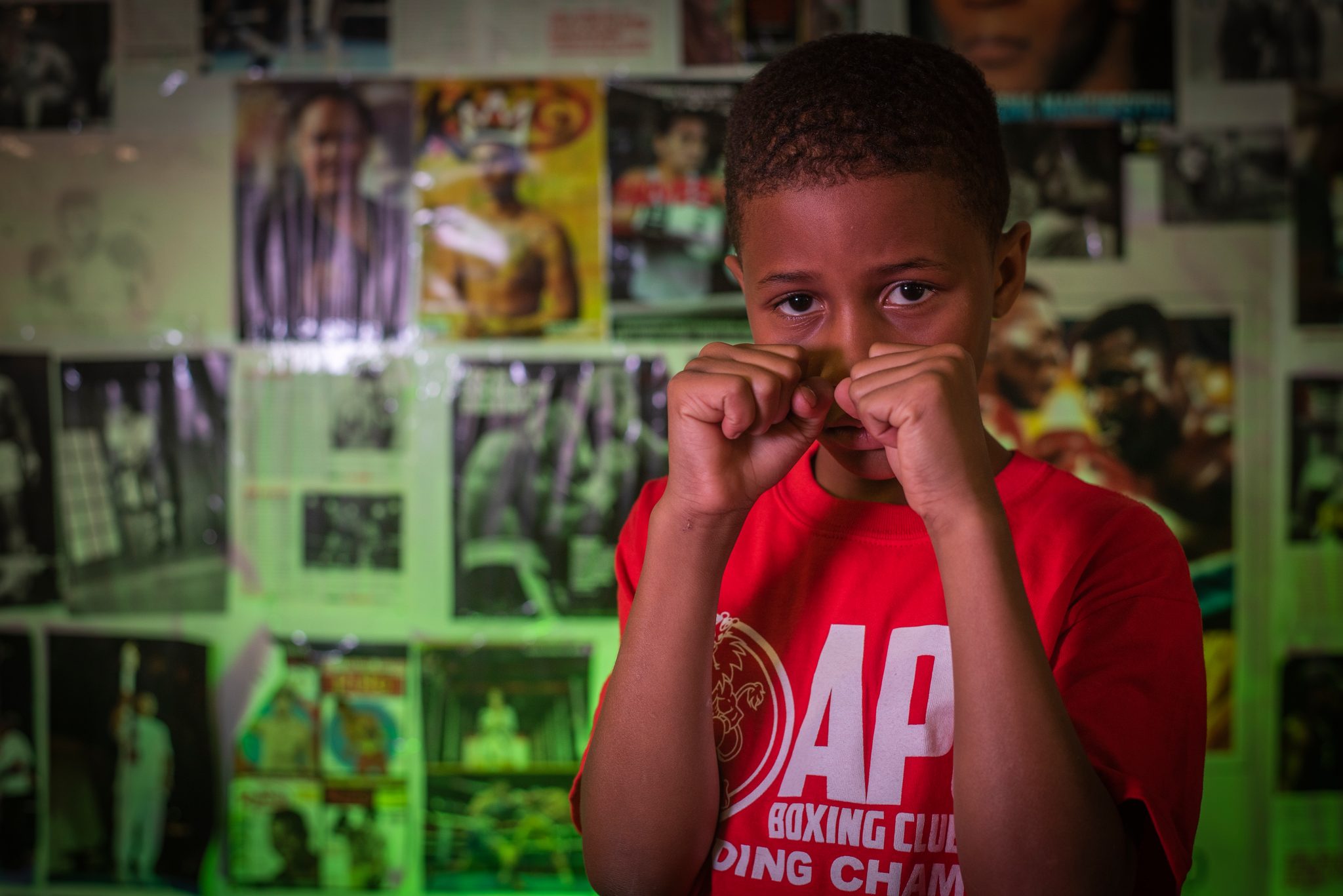 Gloveless fists raised to his face, the posters crowding in behind.