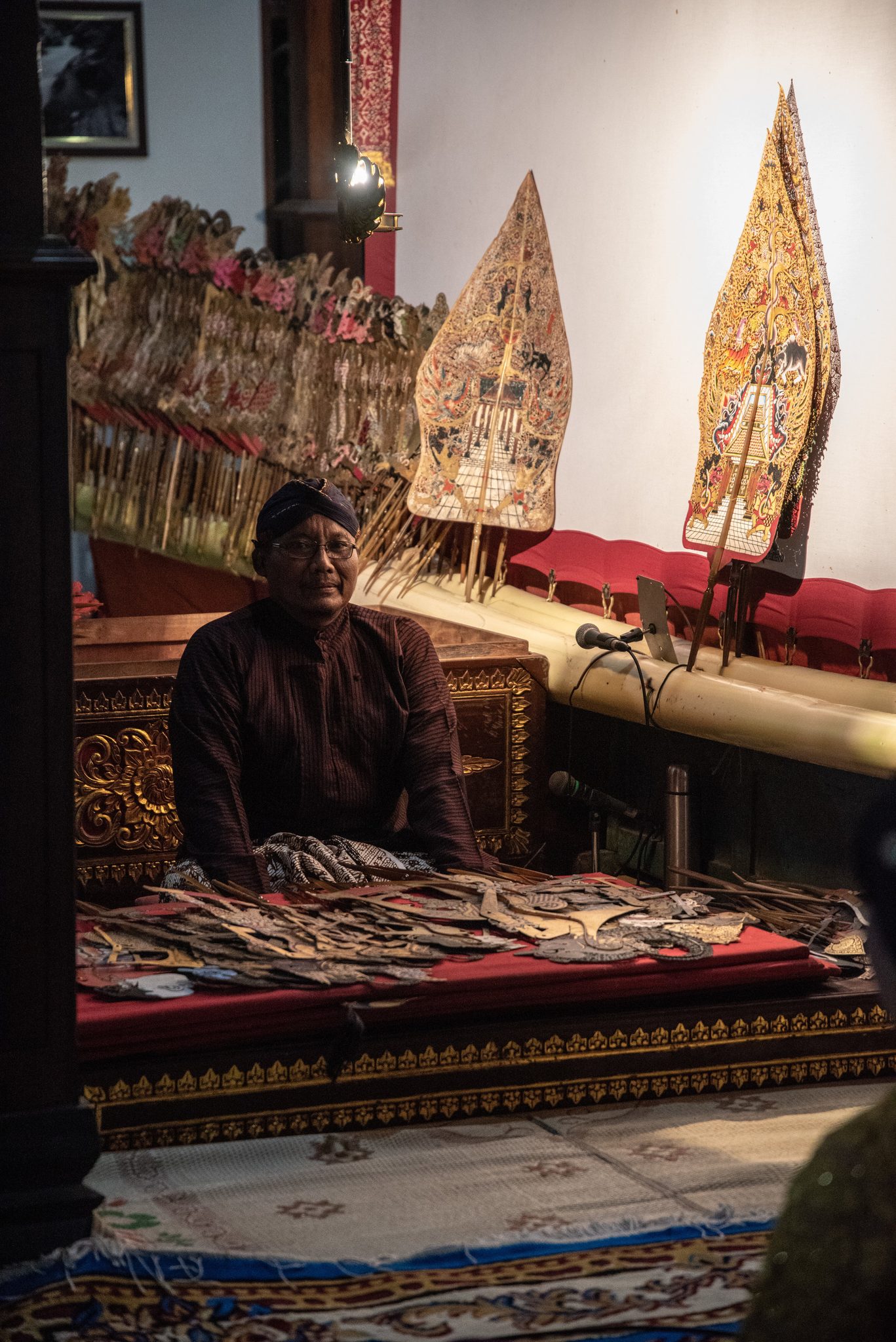 The dalang takes his seat before the screen, the puppets fanned out on the chest in front of him.
