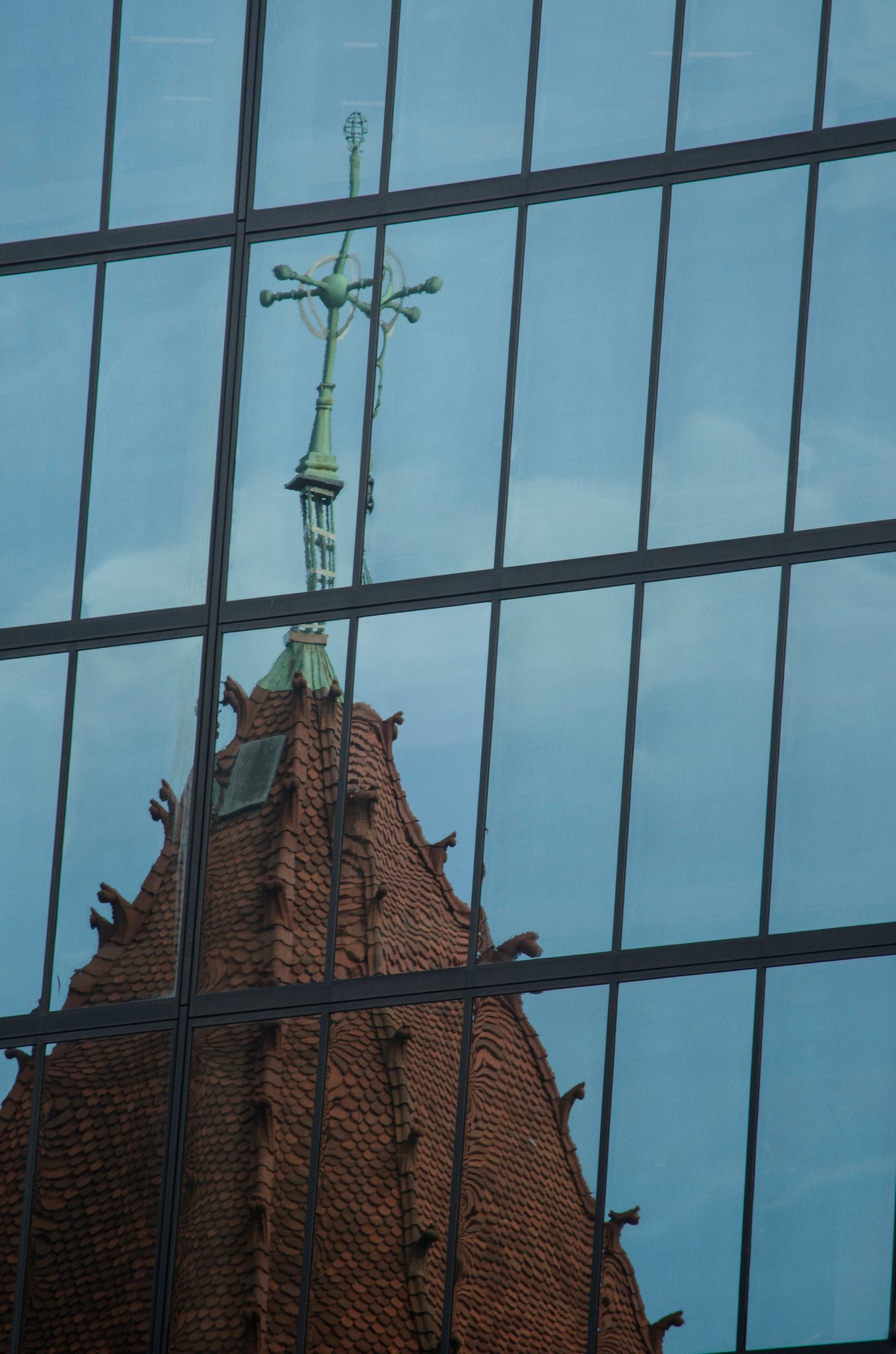 A church spire rises in the reflection of a glass office tower.