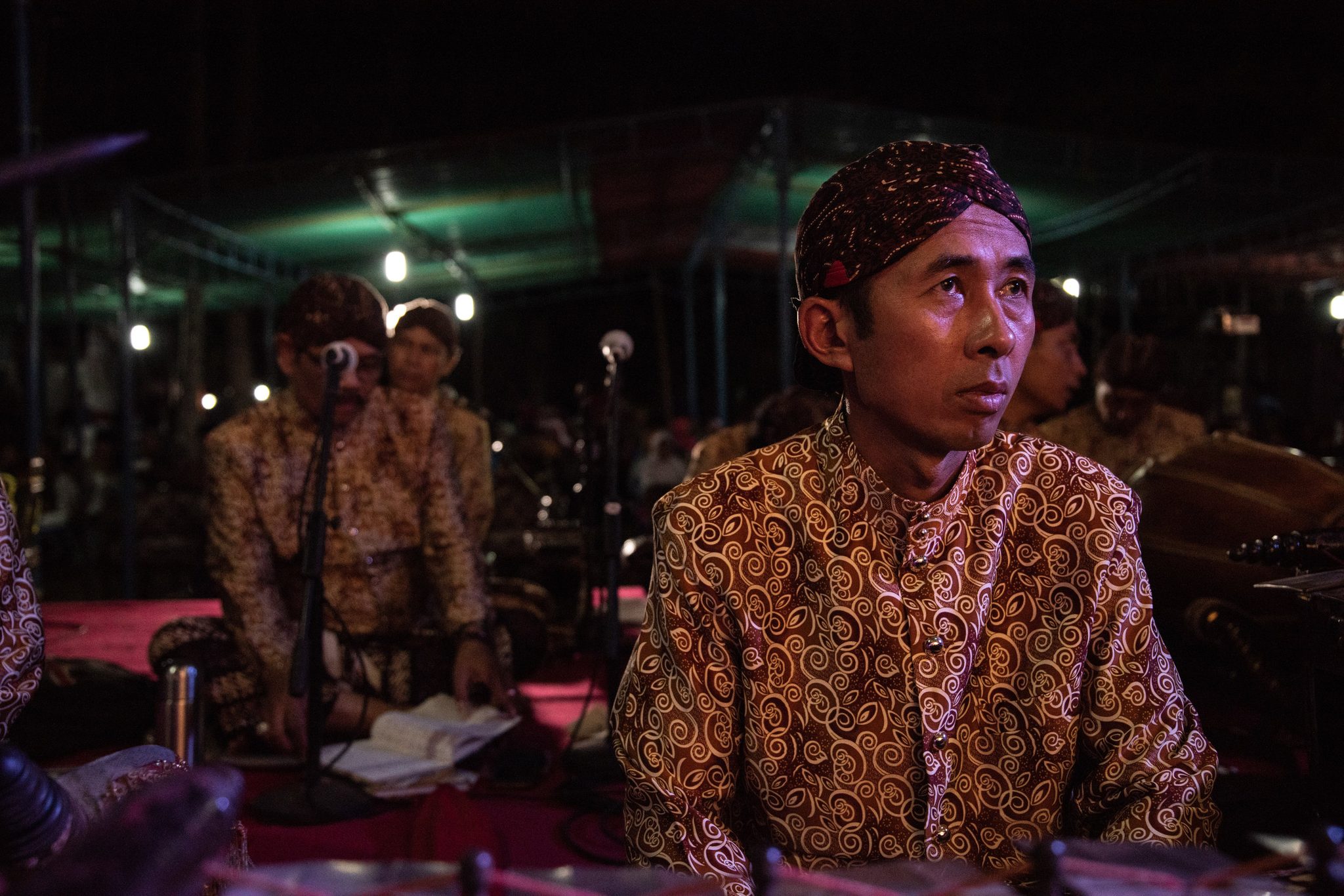 A gamelan player looks up from his instrument, waiting for his cue.