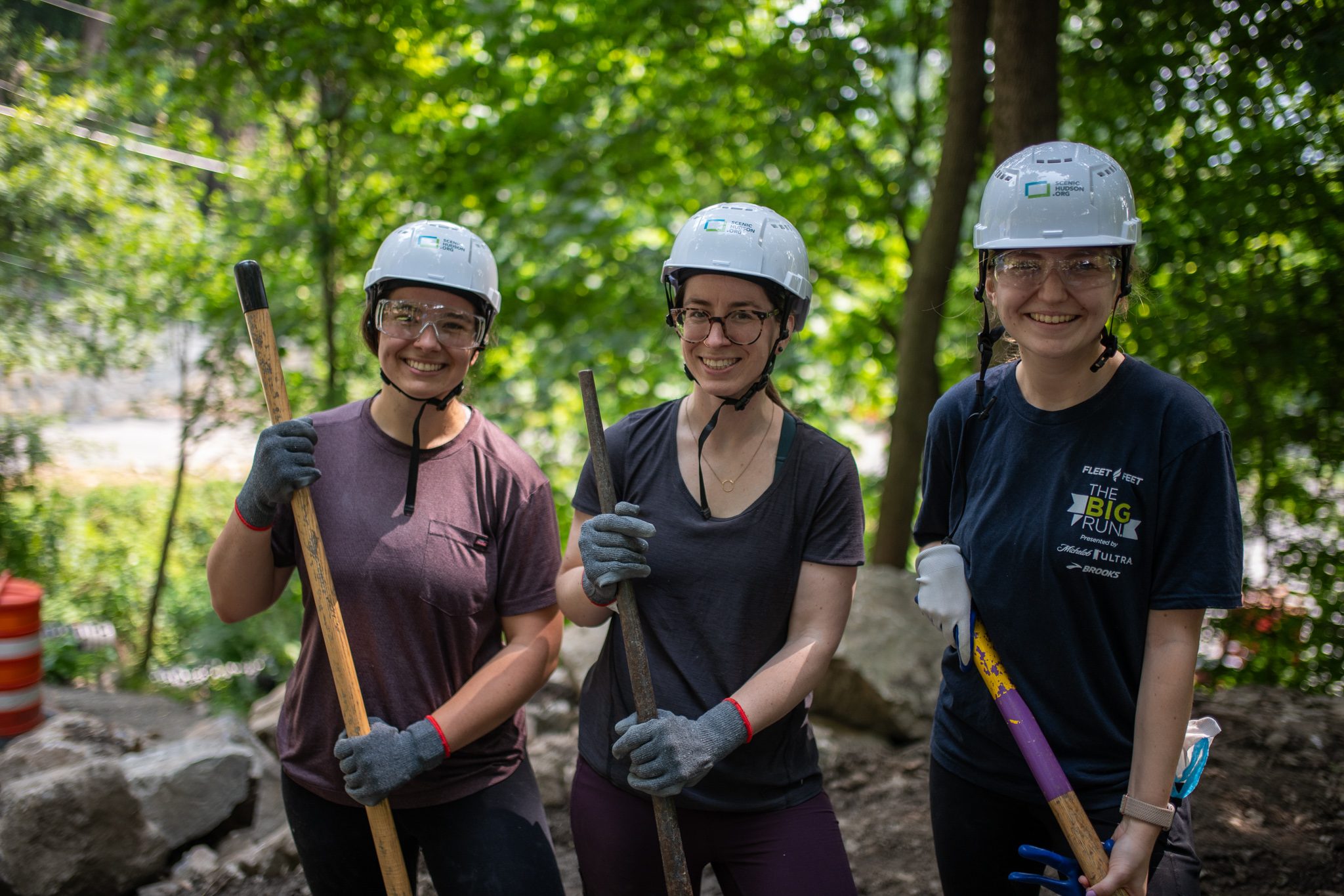 Three crew members lean on their tools and smile.