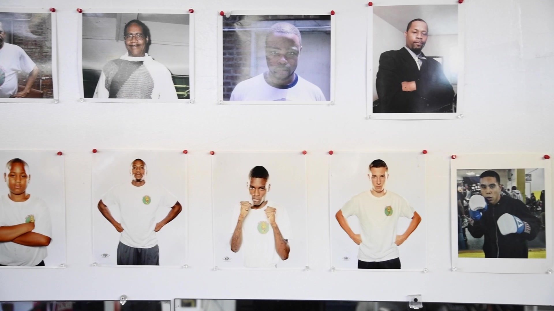 A row of fighter portraits pinned along a white wall, each one squared up and looking straight down the lens.