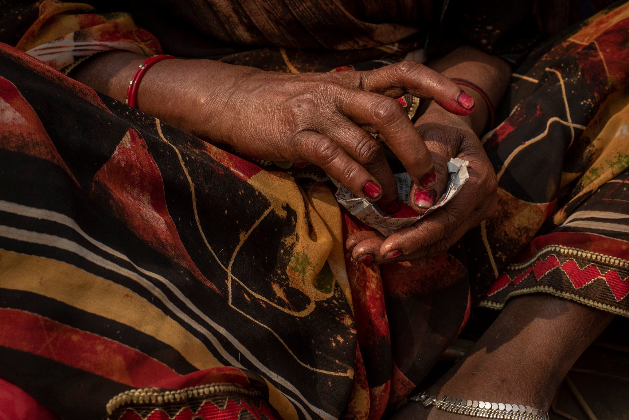 Woman prepares colored pigment to apply a bindi to her forehead