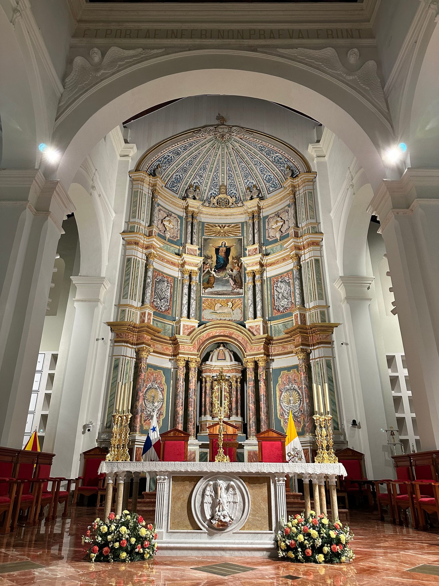 A gilded altar at the end of a white nave.