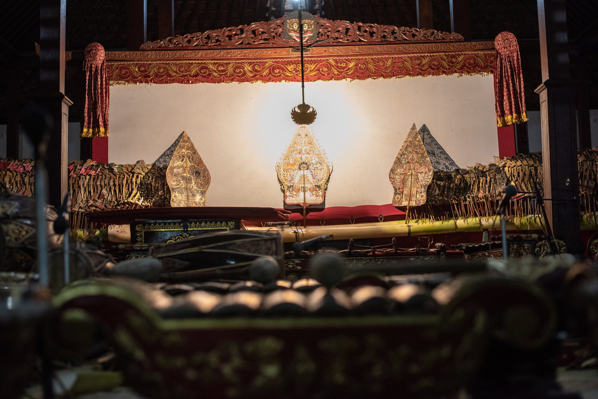 The screen stands ready, three gunungan planted in the banana trunk and the lamp hung above them.