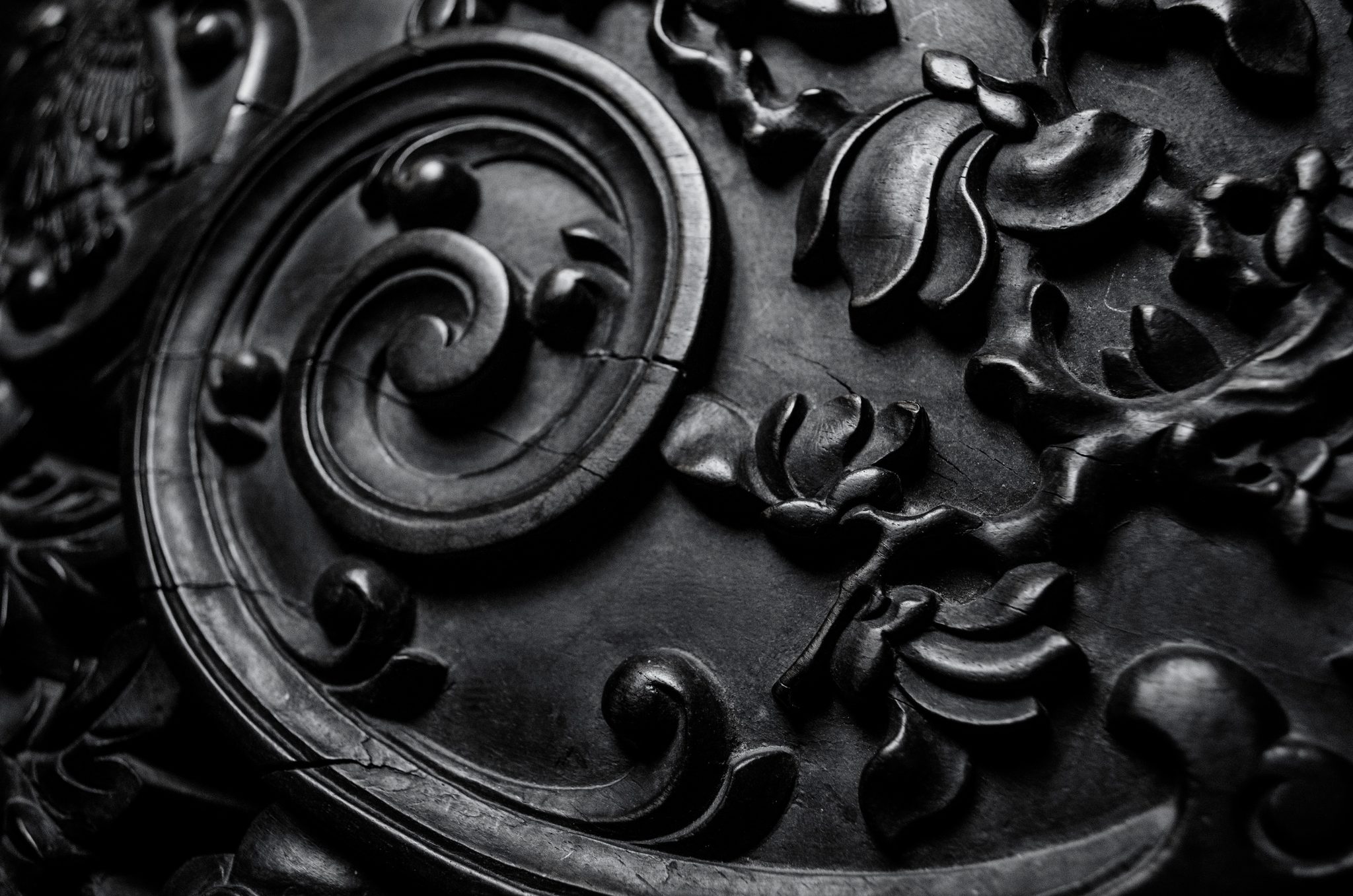 Carved scrolls and leaves in dark wood, in black and white.