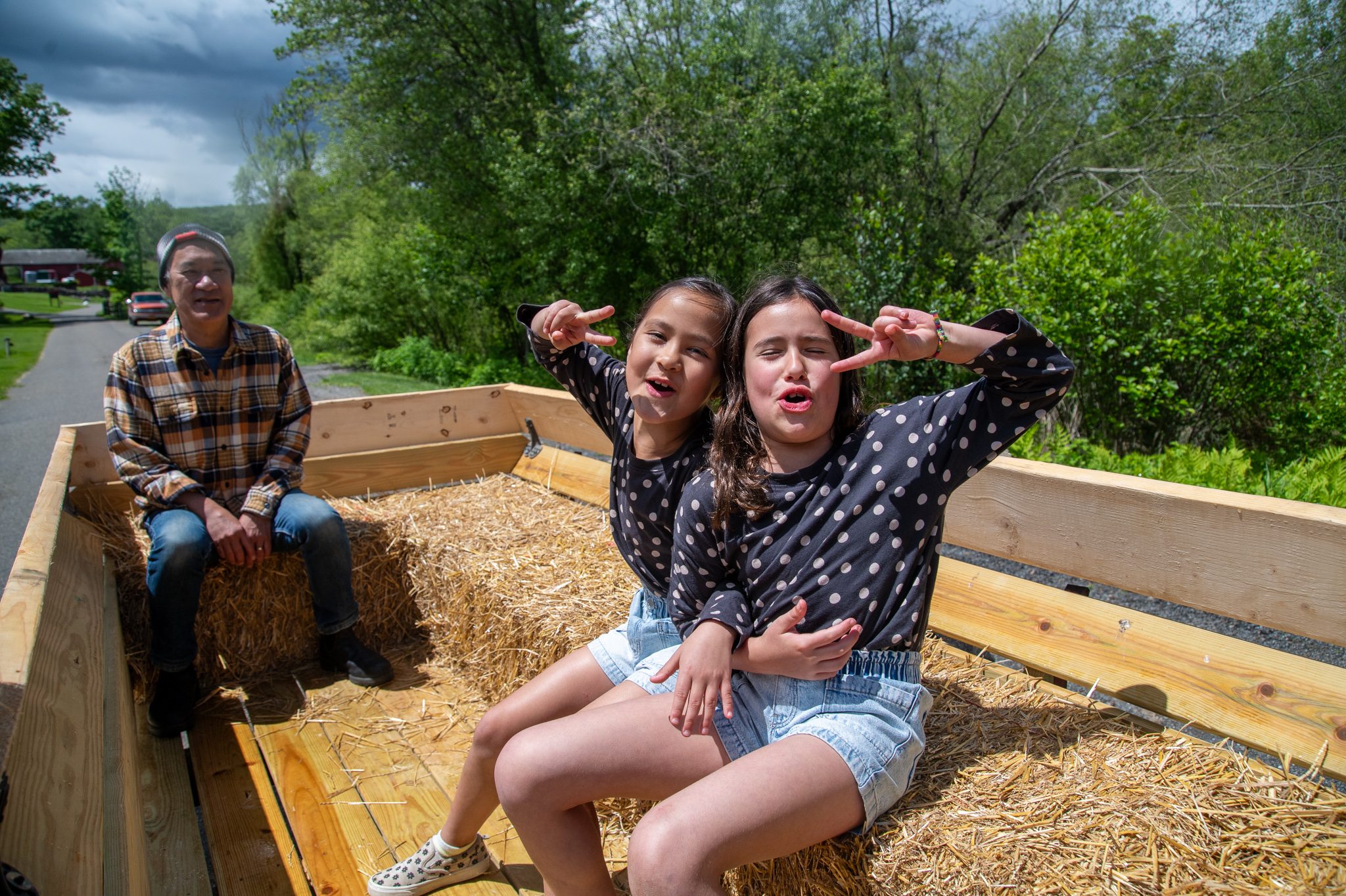 Two girls throw peace signs from the hay wagon.
