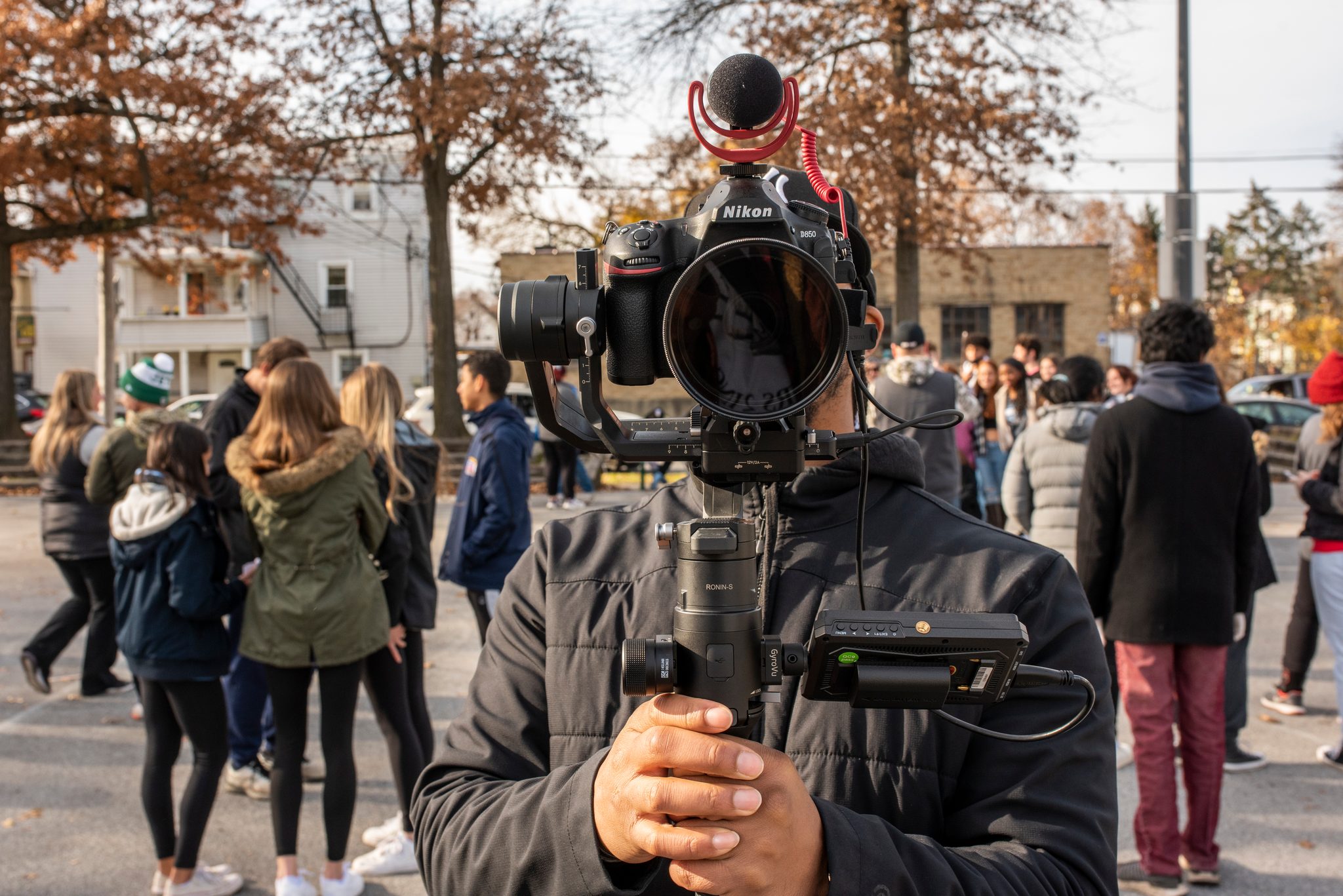 A camera operator rolls on the crowd, gimbal steady and mic up.
