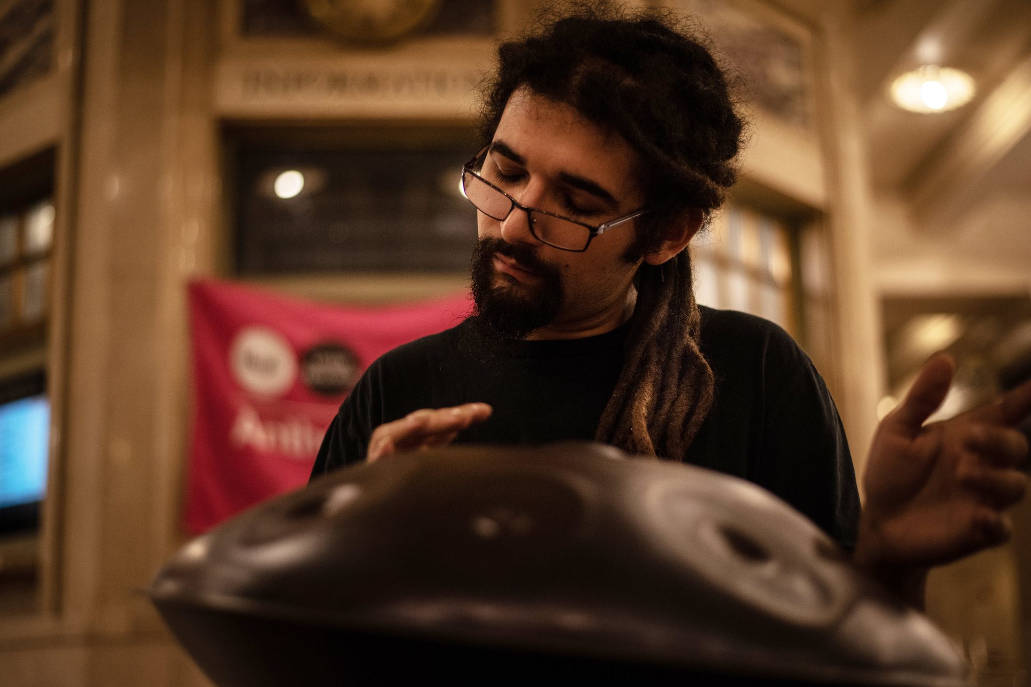 Anthony Carrera leans into the hand pan, his banner glowing behind him.