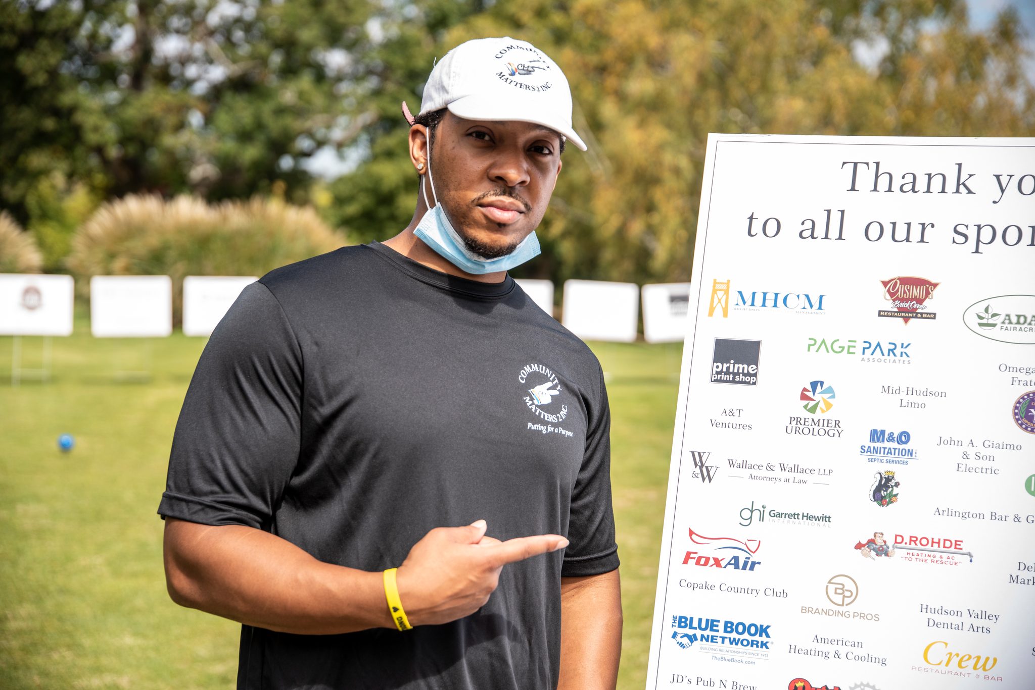 A golfer points out the sponsor board beside the tee.