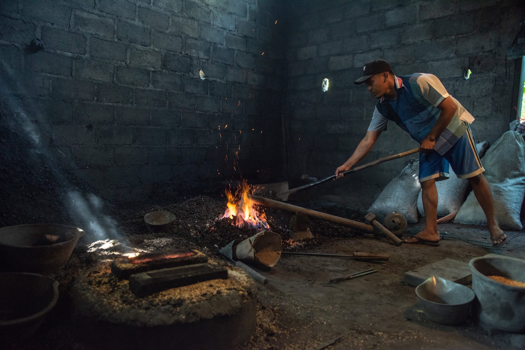Leaning on the long iron, he coaxes the coals back up to heat.