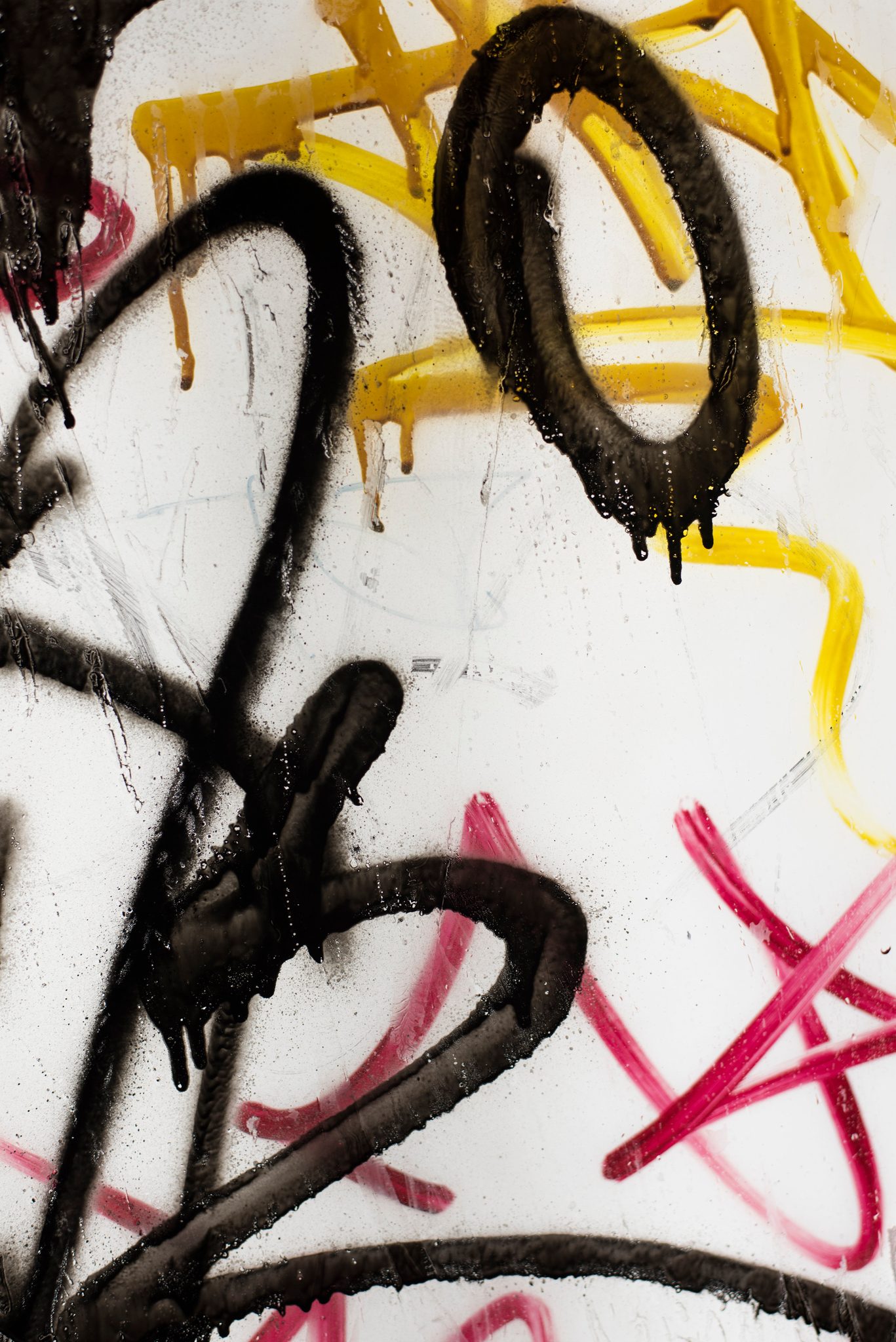 Paint drips over paint in black, yellow and pink.