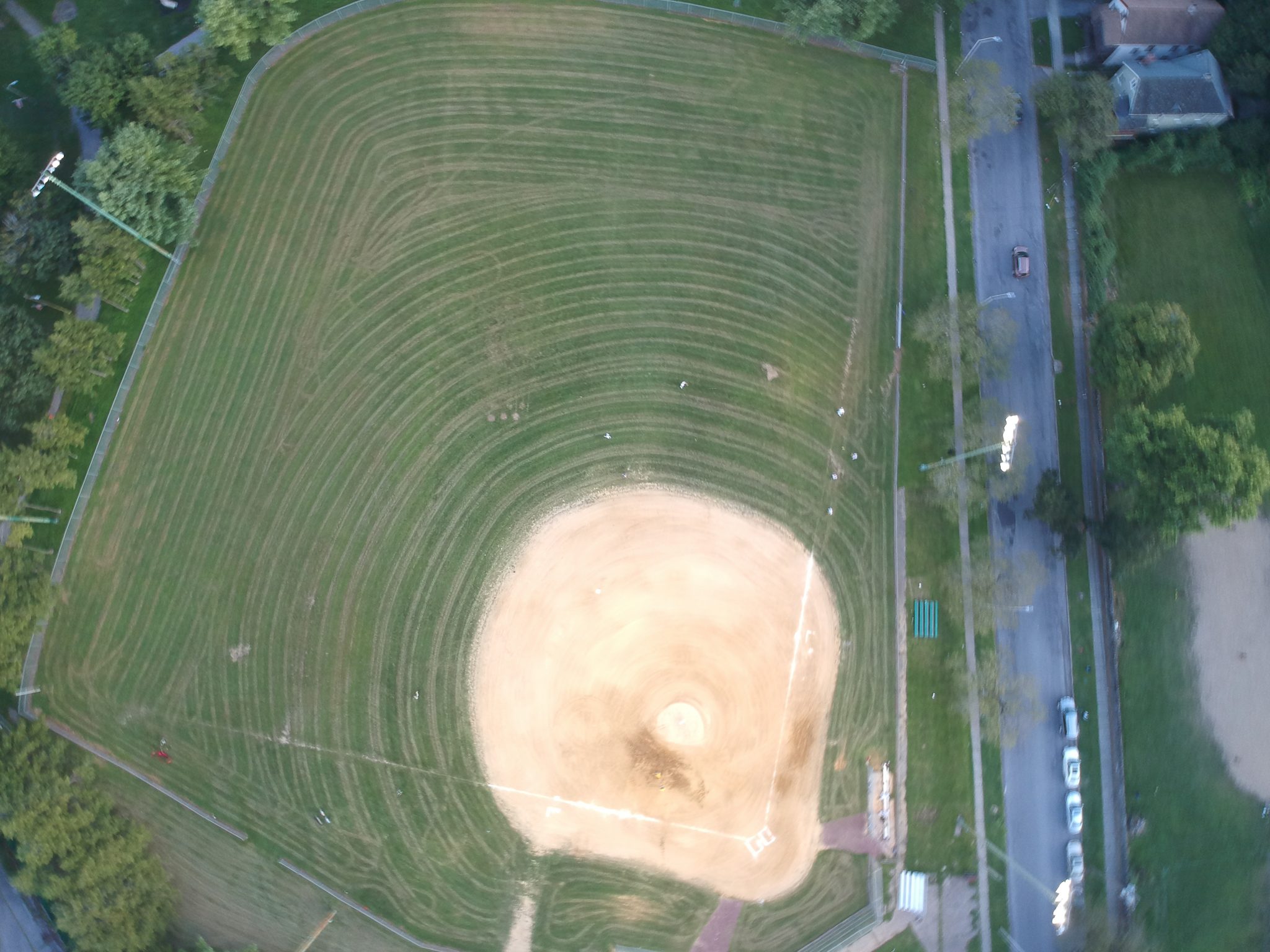 A ballfield seen from straight above, the diamond worn into the grass.